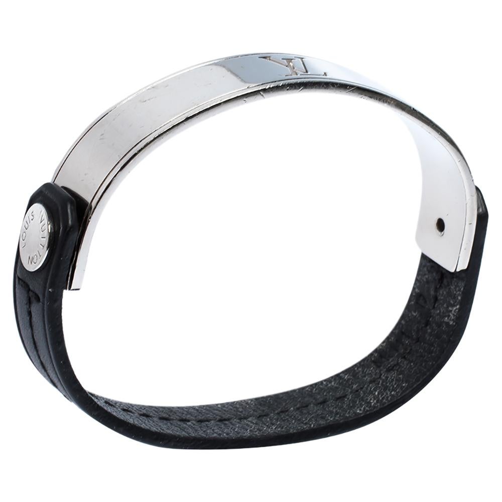 Wonderfully crafted, this smart and stylish Curve it bracelet by Louis Vuitton can be your next prized possession. Featuring the signature LV logo on silver-tone metal band held by black leather straps, the design is finished with a snap button. It