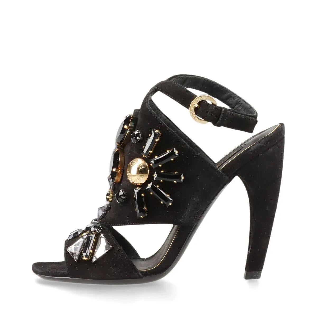 The Louis Vuitton Cut Out Crystal Suede Sandal in black is a striking fusion of elegance and edge. Crafted from rich black suede, the sandals feature intricate cut-out detailing that creates a modern, sculptural silhouette. Sparkling crystals are