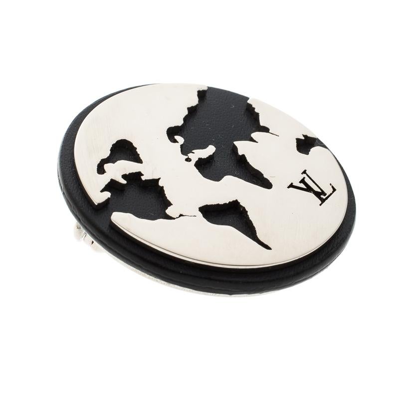 This exquisite pin brooch by Louis Vuitton is the best accessory for any of your exclusive evening wear ensembles. It is cut to a round shape rendered in black leather and accented with cut out silver-tone metal to create the look of a world map.