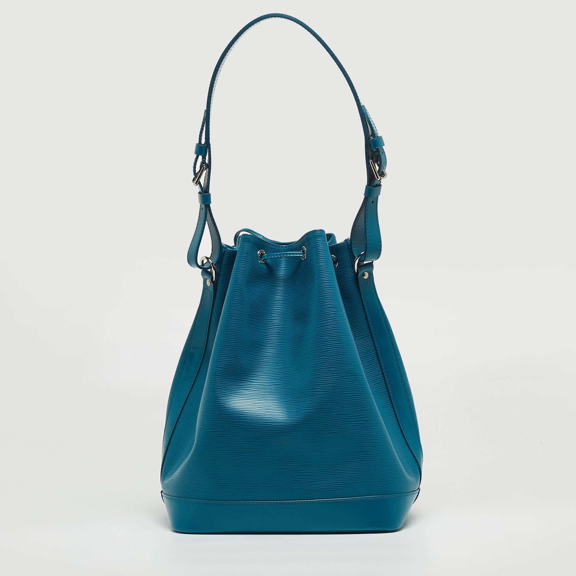 The Louis Vuitton Noe Bag is an exquisite accessory. Crafted from textured cyan epi leather, it features a drawstring closure, silver-tone hardware, and an adjustable shoulder strap. The iconic LV craftsmanship adds a touch of luxury to this