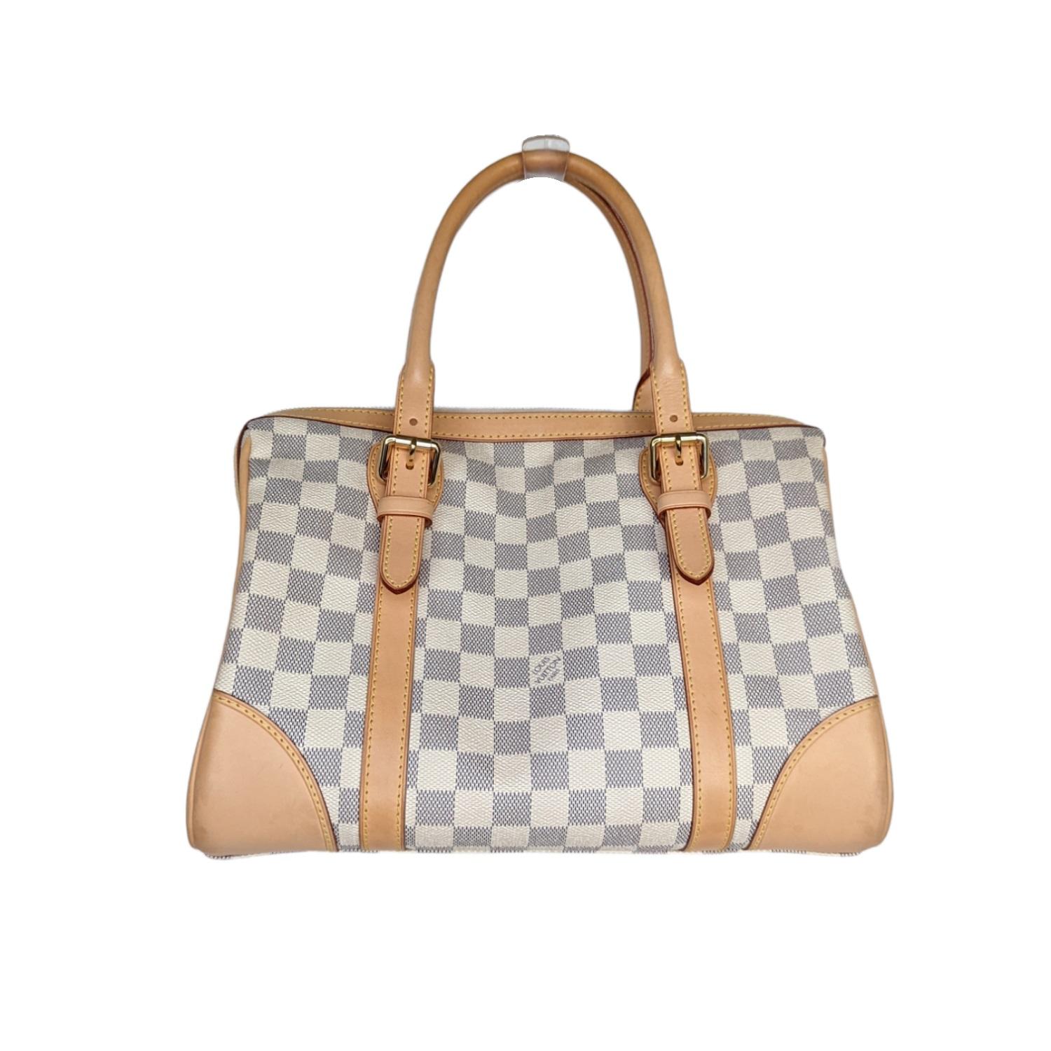 This stylish handbag is crafted of signature Damier checkered canvas in blue and white, with vachetta cowhide leather trim. The bag features adjustable rolled leather top handles, external side pockets and polished brass hardware, including a Louis