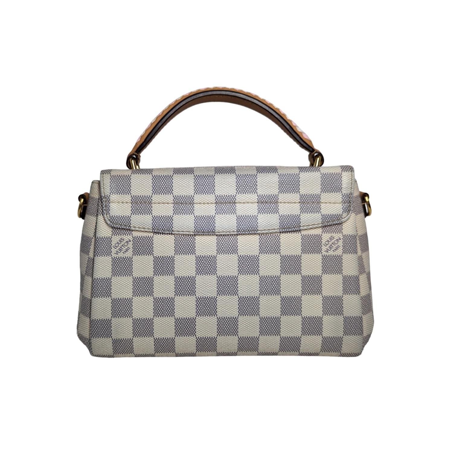 Louis Vuitton Damier Azur Braided Croisette in Rose. This compact tote is crafted of Louis Vuitton Damier coated canvas in blue and white with white and pink leather accents on the handle and shoulder strap. The bag features signature vachetta
