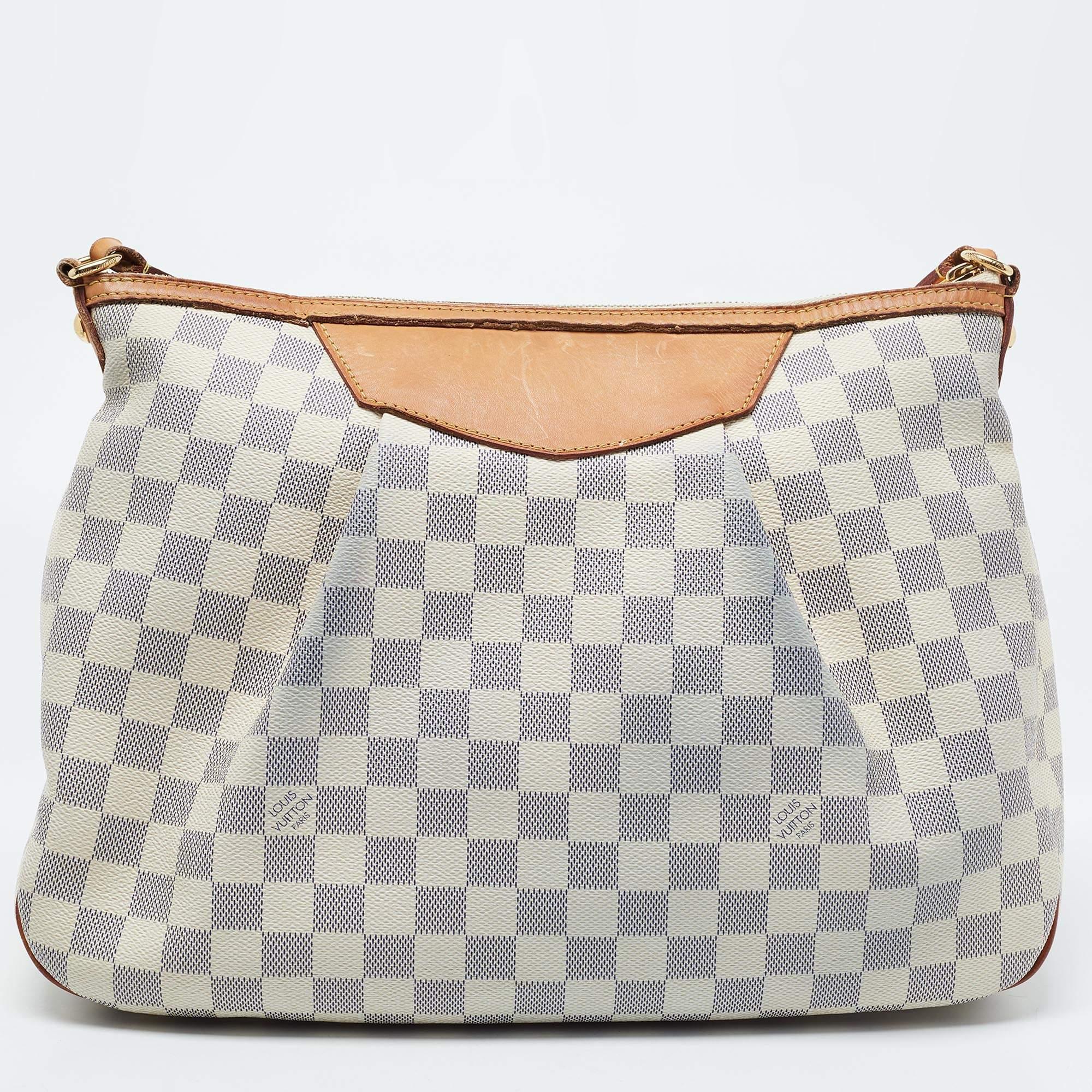 Louis Vuitton’s Siracusa MM bag is a sophisticated accessory. It is created using Damier Azur canvas & leather on the exterior and comes with gold-tone metal fittings. It comes with an adjustable shoulder strap. Like every other LV creation, this