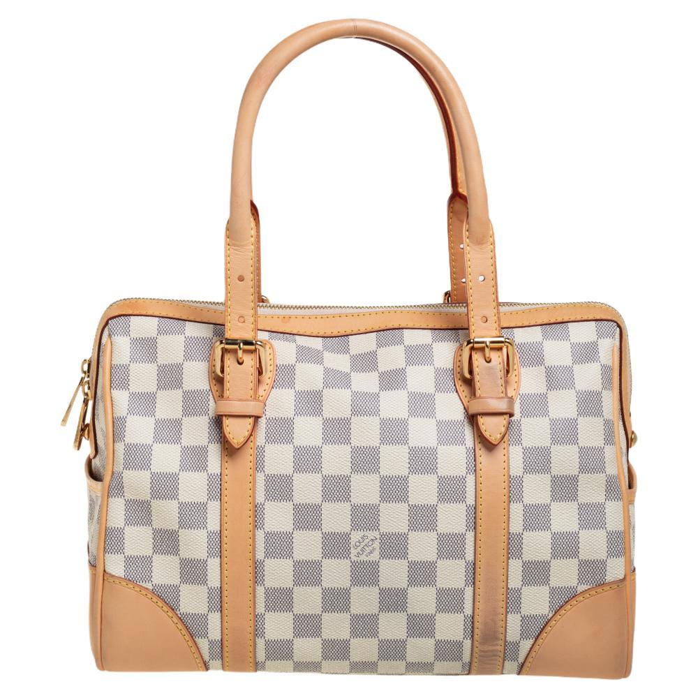 This Loius Vuitton Berkeley bag flaunts the designer's rich heritage. Elegantly structured from Damier Azur canvas, this LV creation is styled with leather trims and dual handles. The top zip closure opens to an Alcantara-lined interior housing a