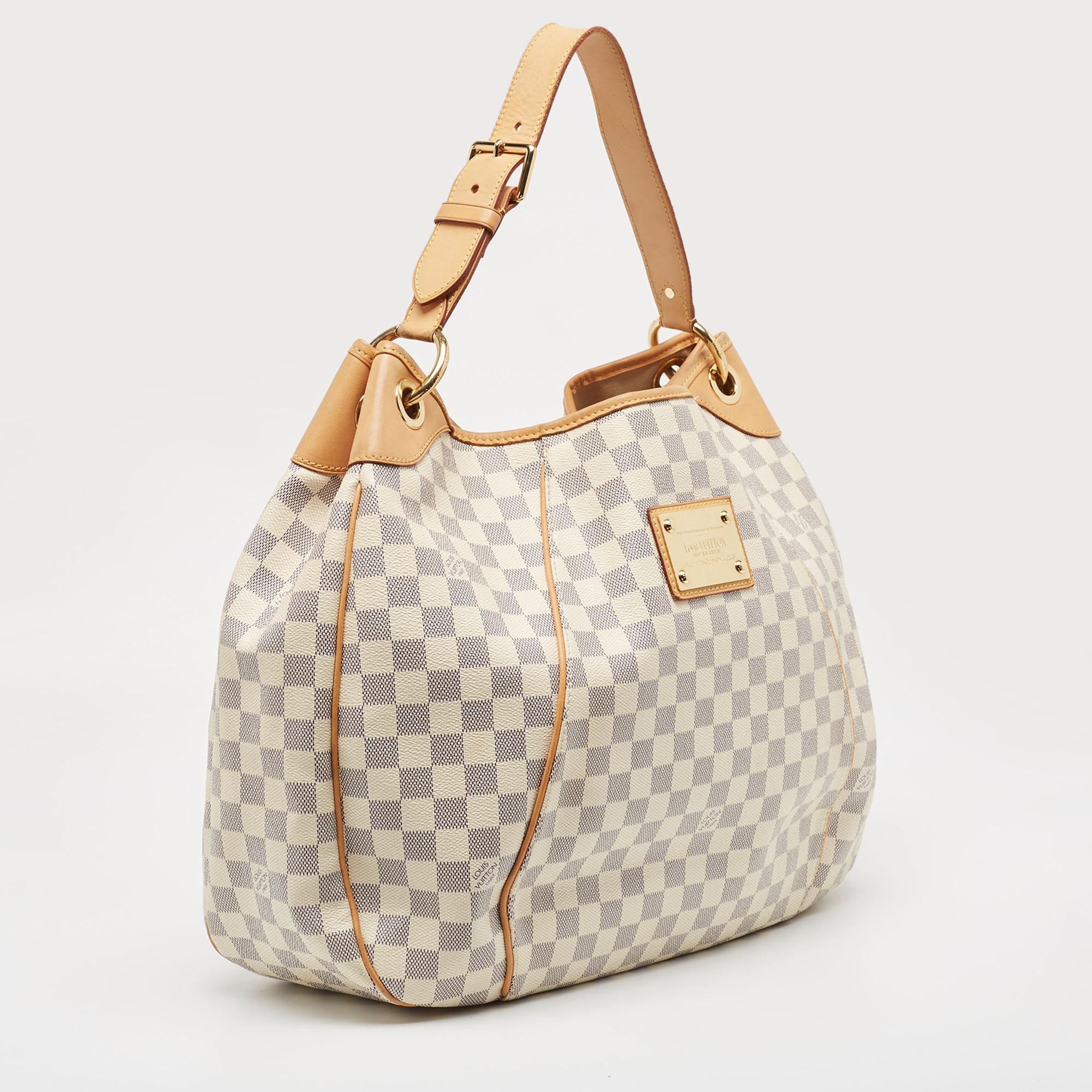 Your dream to own an appealing Louis Vuitton handbag has come true in this gorgeous piece. Crafted from Damier Azur canvas, this bag features a single handle, a snap button, and gold-tone hardware. While the front brand plaque elevates its beauty,