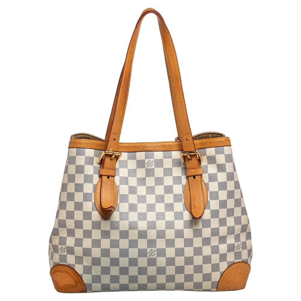 Handbags from Louis Vuitton enjoy widespread popularity owing to their high style and functionality. This Hampstead bag is no exception. Crafted from their signature Damier Azur coated canvas and leather, the bag comes with two flat top handles and