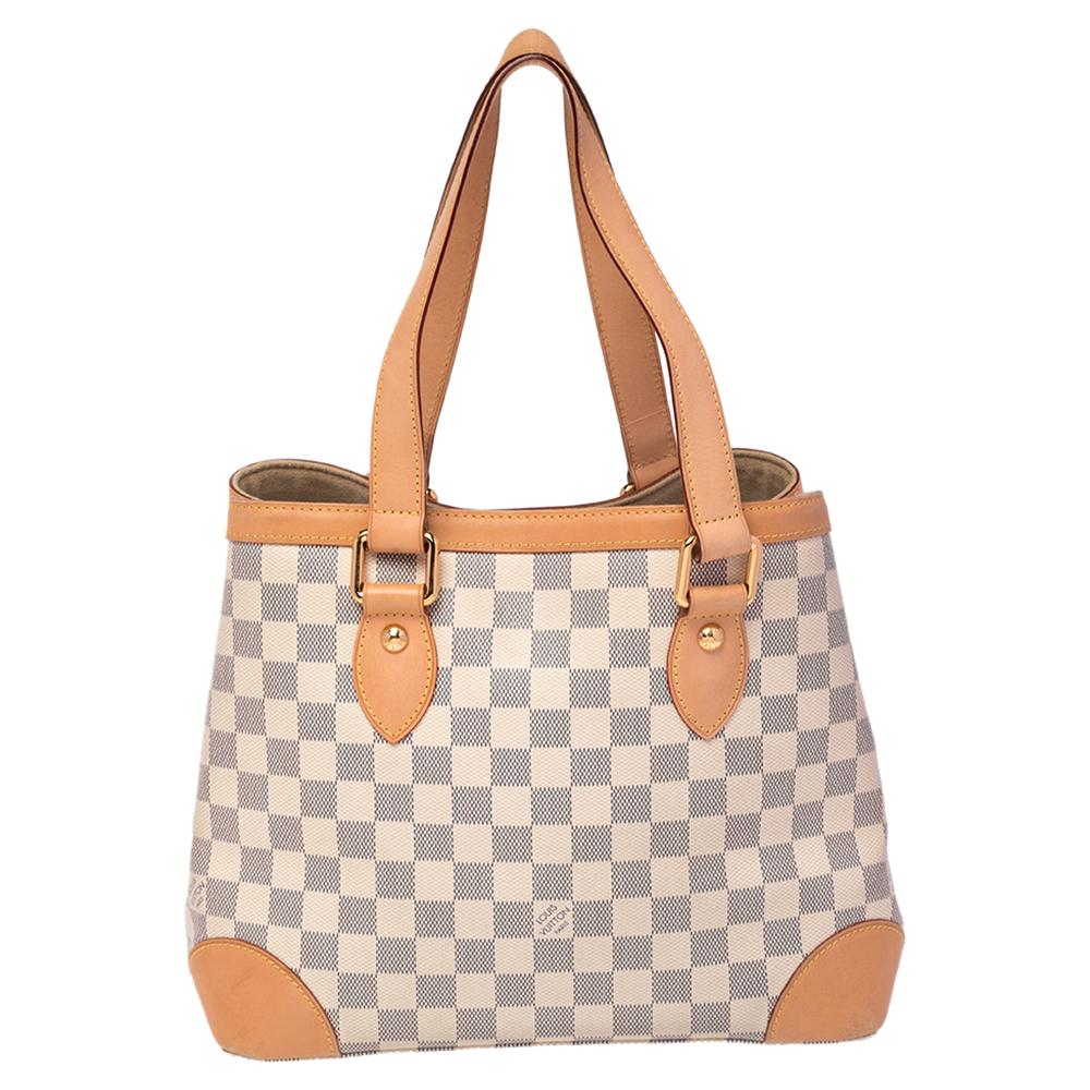 Handbags from Louis Vuitton enjoy widespread popularity owing to their high style and functionality. This Hampstead bag is no exception. Crafted from their signature Damier Azur canvas, the bag comes with leather trims, two flat top handles, and a