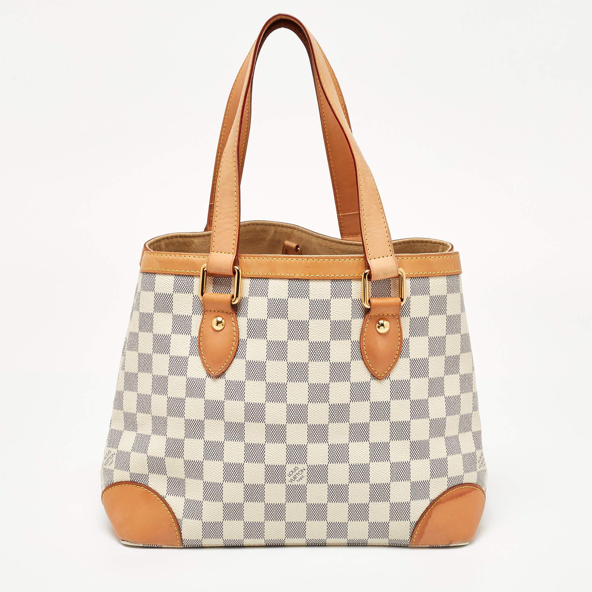 Handbags from Louis Vuitton enjoy widespread popularity owing to their high style and functionality. This Hampstead bag is no exception. Crafted from their signature Damier Azur and leather, the bag comes with two flat top handles and a hook clasp