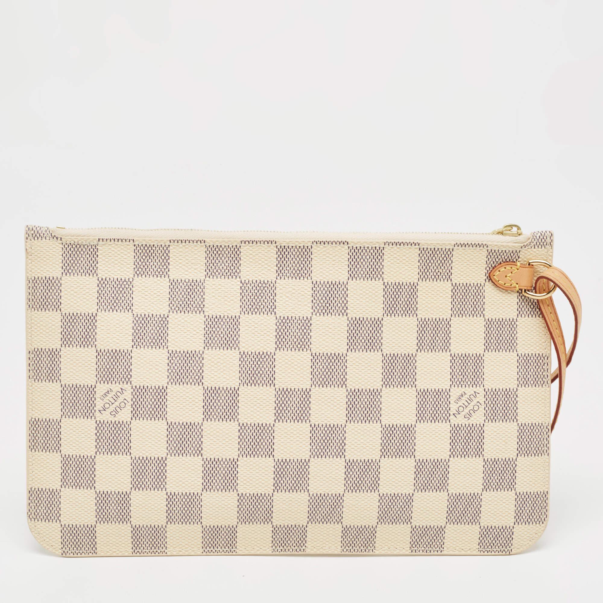 The exclusive Neverfull pochette from the house of Louis Vuitton is a stylish way to carry your basics. The pochette is crafted from the signature Damier Azur canvas body that imparts grace, while the gold-tone top zip closure adds the perfect