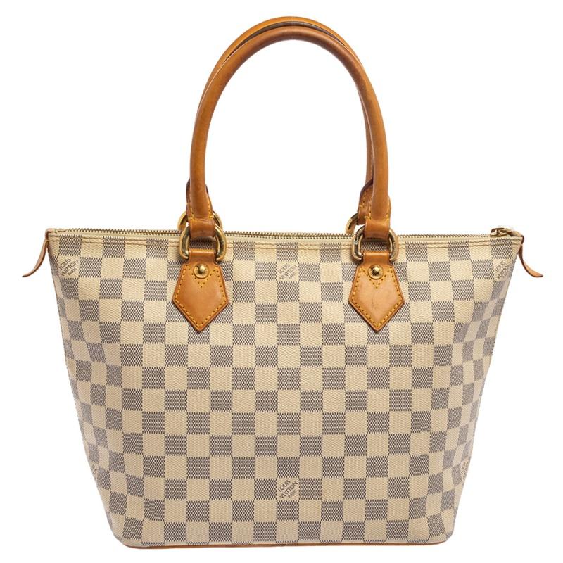 This Saleya PM by Louis Vuitton will add ease to your daily routine. Crafted from Damier Azur canvas with beige leather trim and piping, it features a top zipper closure, dual handles, and polished gold-tone hardware. The Alcantara-lined interior