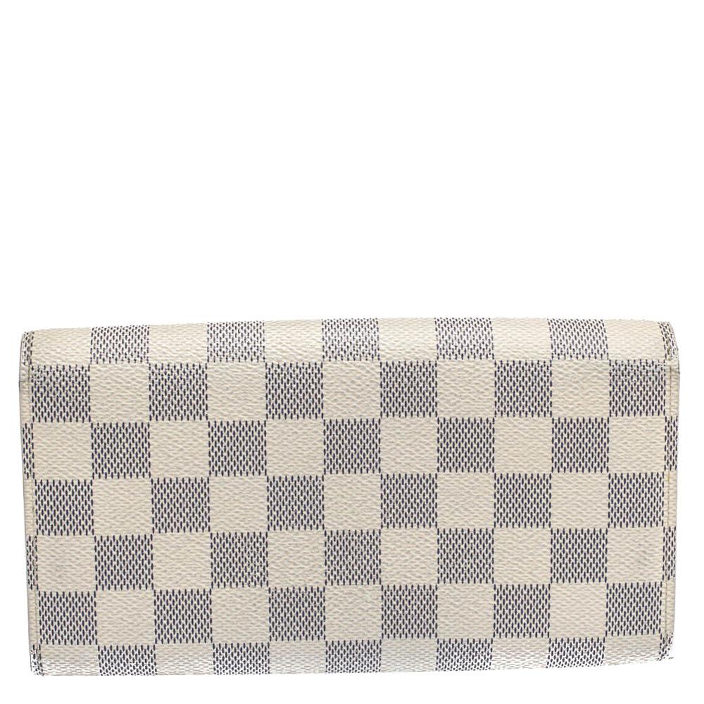 One of the most famous wallets by Louis Vuitton is the Sarah. This one here comes made from Damier Azur canvas and the button on the flap opens to an interior with multiple card slots and a zip pocket. Perfect in size, this wallet can easily fit