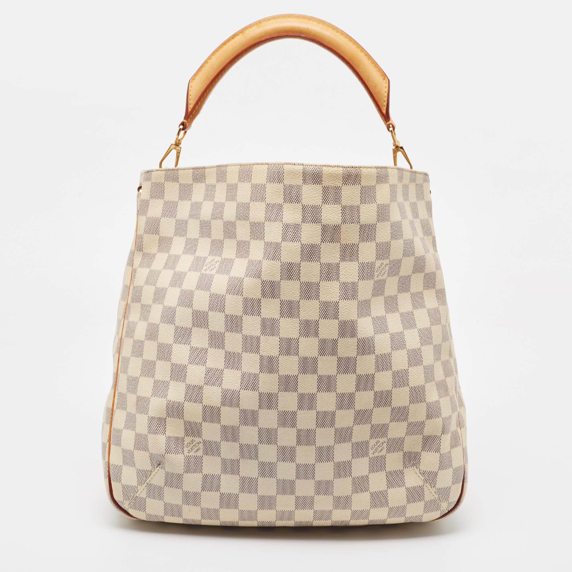 This Soffi bag from the House of Louis Vuitton is a chic accessory to own. It is crafted using Damier Azur canvas on the exterior and flaunts gold-toned hardware. It features a single handle and a roomy canvas-lined interior. Style this gorgeous LV