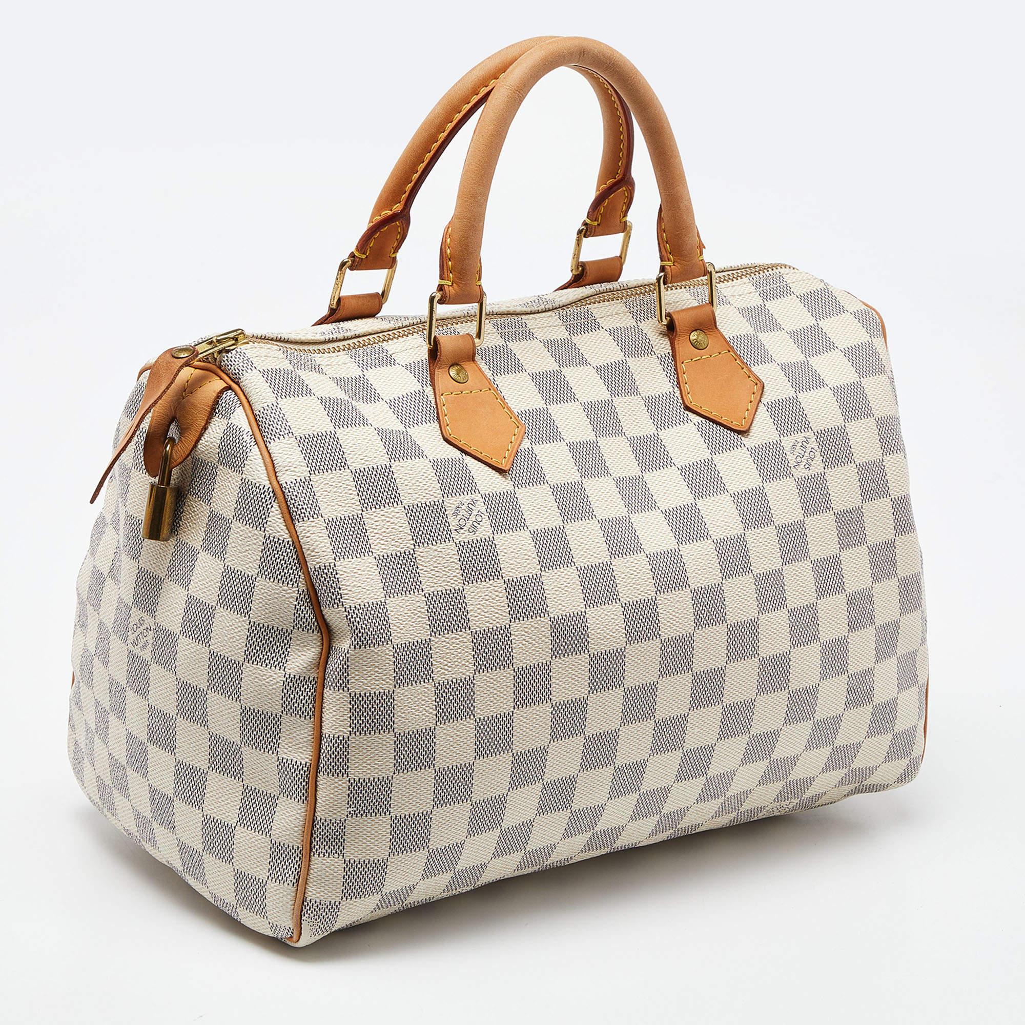 Louis Vuitton's handbags are popular owing to their high style and functionality. This bag, like all their designs, is durable and stylish. Exuding a fine finish, the LV Damier Azur Speedy 30 bag is designed to give a luxurious experience. The