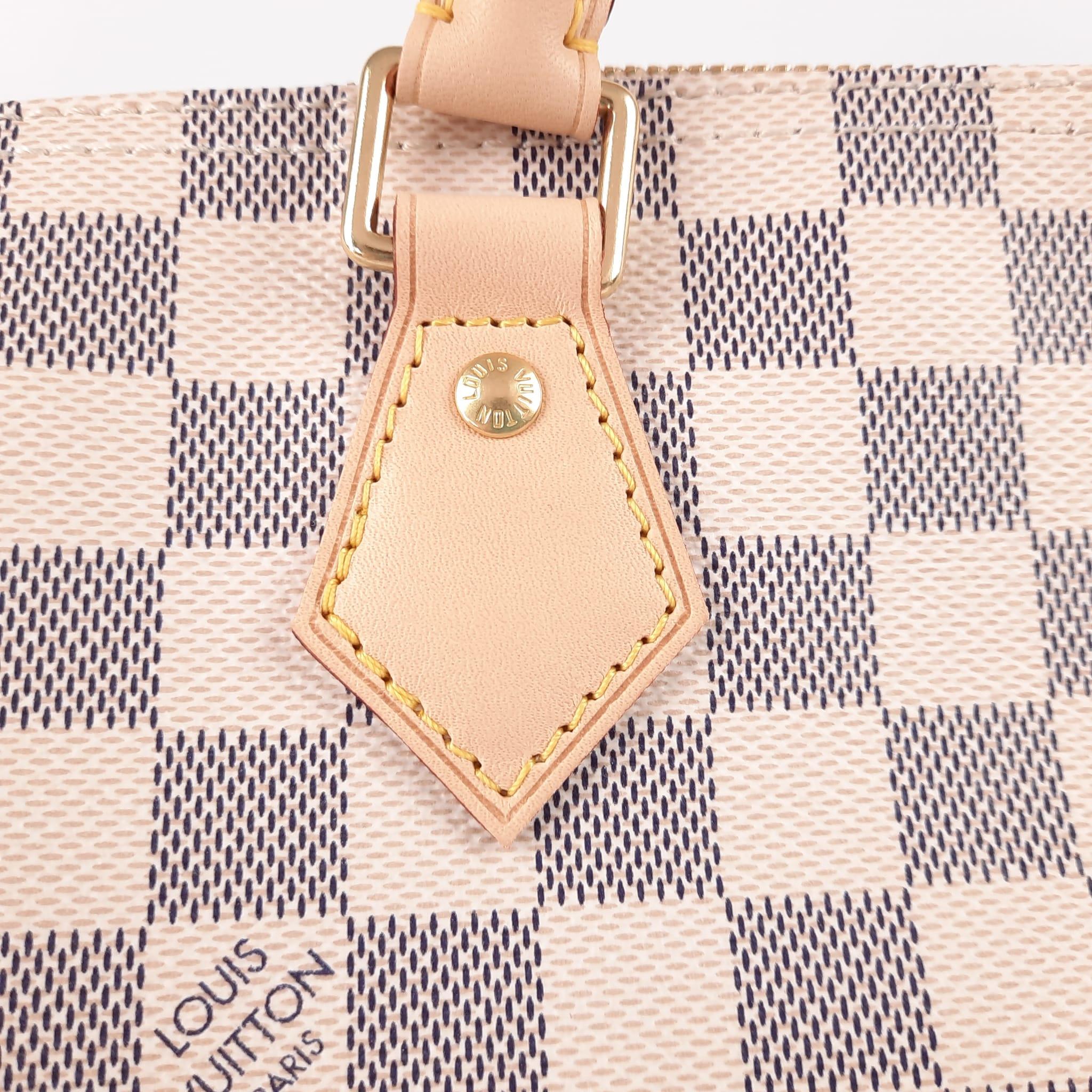 Fashioned from luminous Damier Azur canvas, the Speedy 30 is an elegant, compact handbag; a stylish companion for city life.
rolled leather handles and engraved, signature padlock.