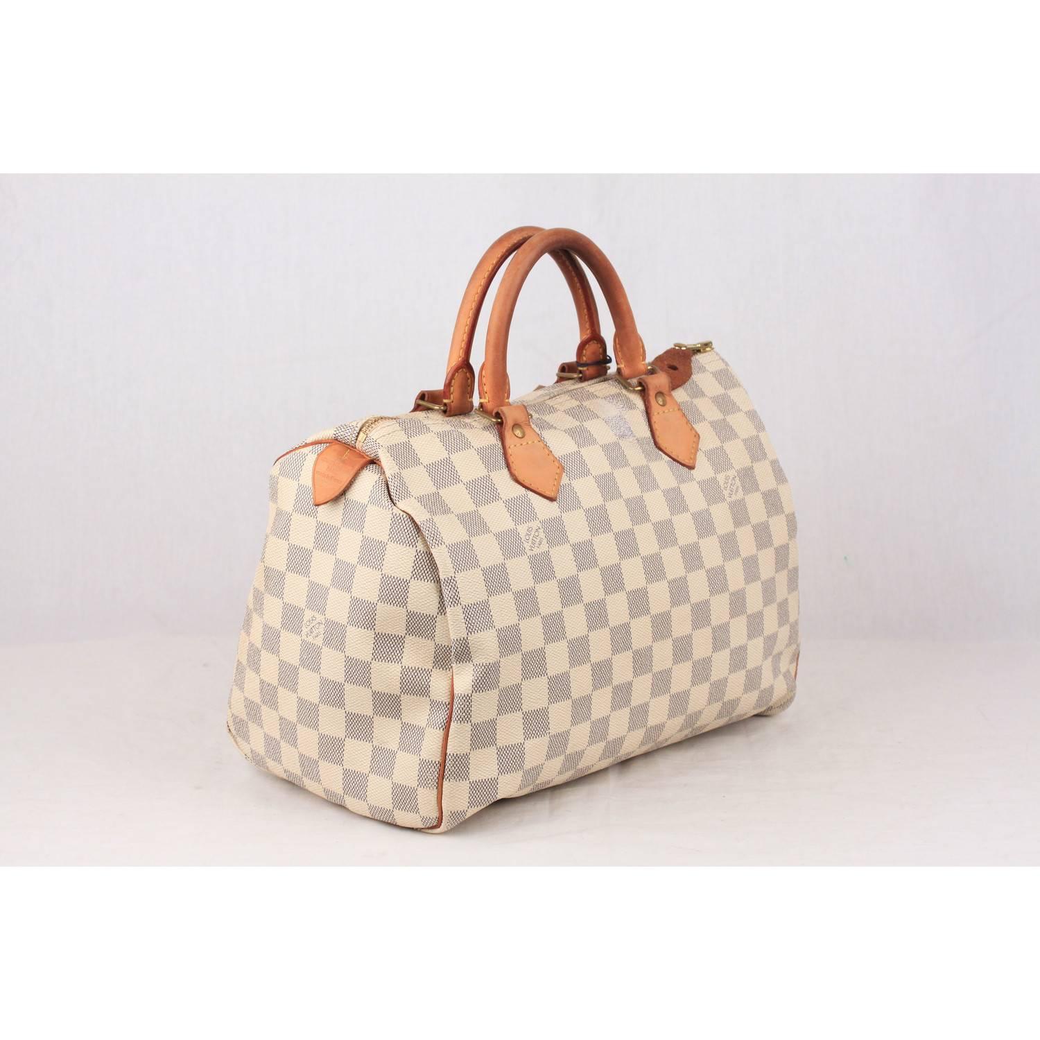 Iconic Louis Vuitton SPEEDY 30 in DAMIER AZUR canvas. Beige fabric lining and 1 side open pocket inside. Beige leather handles and piping. Gold tone hardware. Interior pocket and D-ring for keys and accessories. Original padlock included (keys are