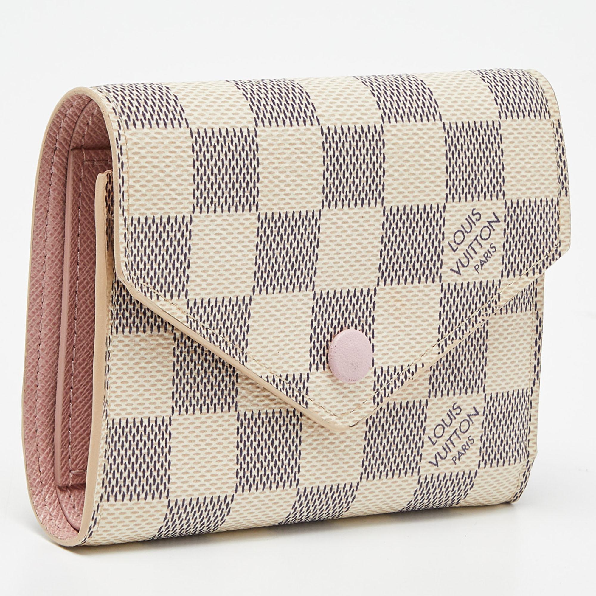 Basic essentials can be carried effortlessly in this feminine and functional Victorine wallet by Louis Vuitton. This compact wallet is crafted from the brand's iconic Damier Azur canvas with leather lining. It offers quick and secure access to