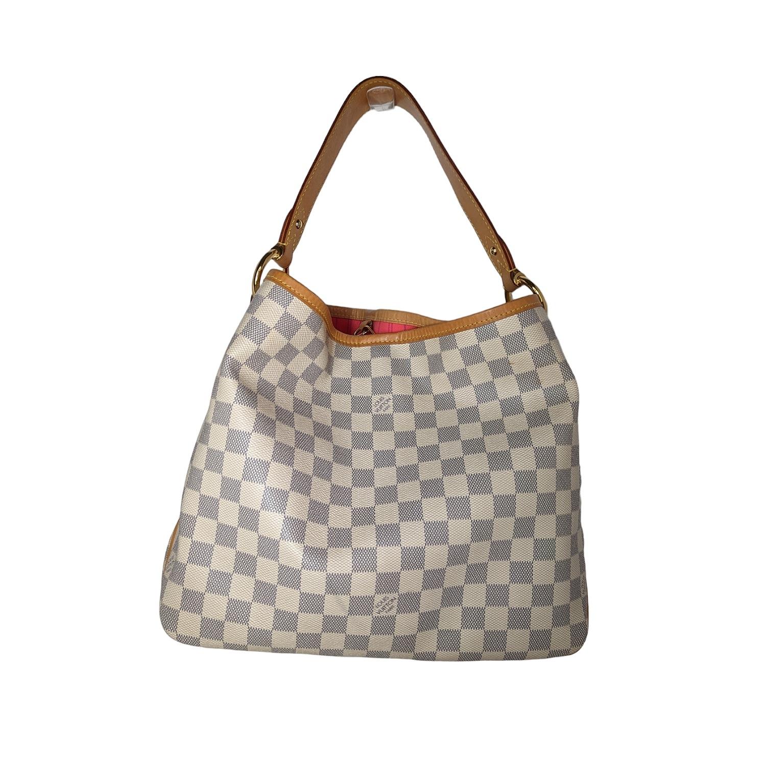 This stylish shoulder bag is finely crafted of classic Louis Vuitton Damier canvas in blue and white. The bag features a looping vachetta cowhide leather shoulder strap and trim, with polished brass hardware. The top opens to a hot pink striped