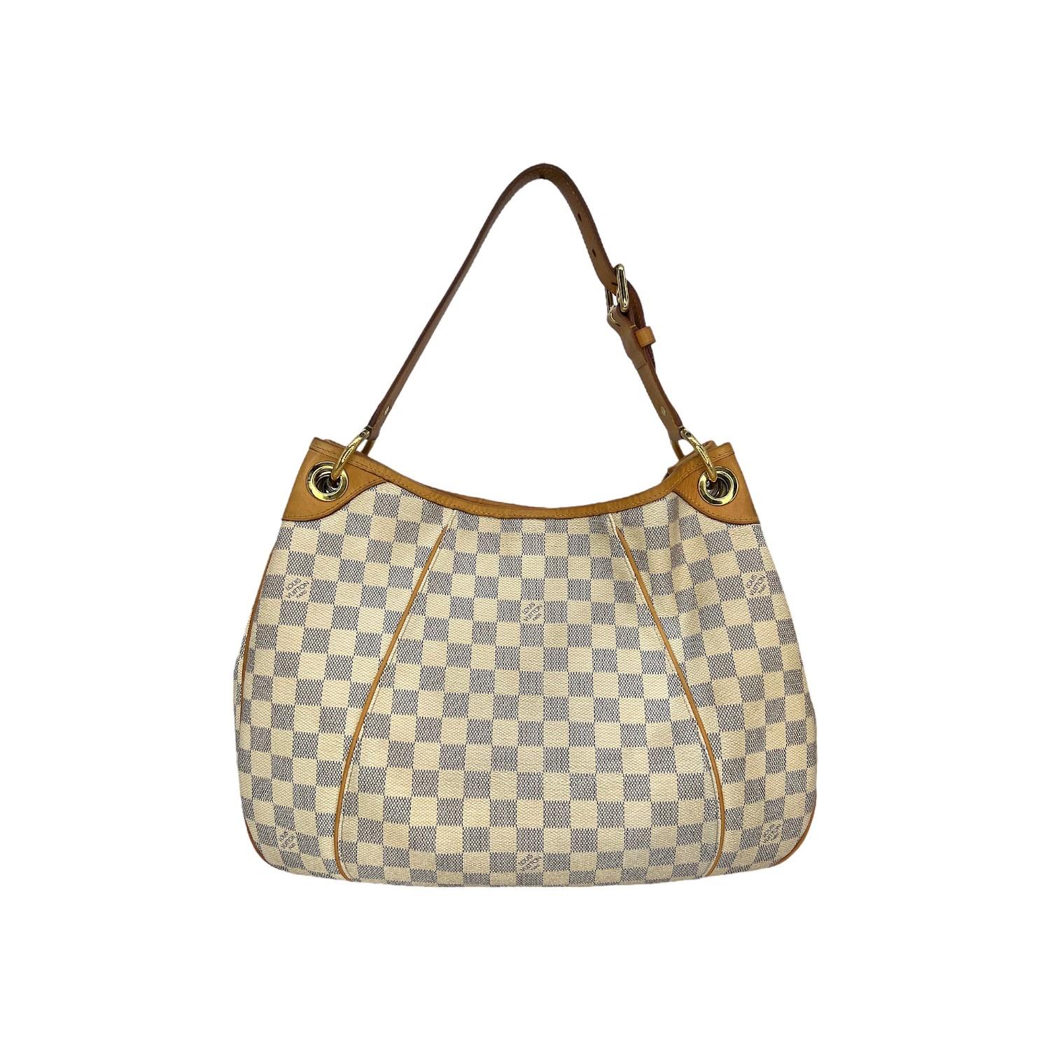 This Louis Vuitton Galleria PM was made in the USA and it is crafted of the Louis Vuitton Damier Azur coated canvas exterior with leather trimming and gold-tone hardware features. It features a magnetic snap closure that opens up to an Alcantara
