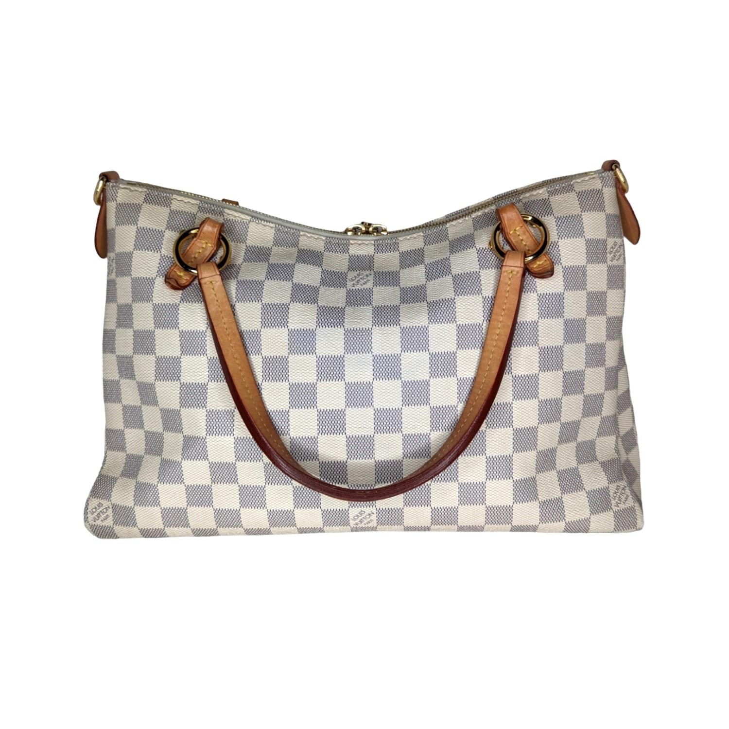 The sophisticated handbag has a distinctive structure and is featured here in lovely Louis Vuitton Damier Azur blue and white checkered canvas. There is complementary signature Vachetta cowhide leather including leather top handles, two tassels and