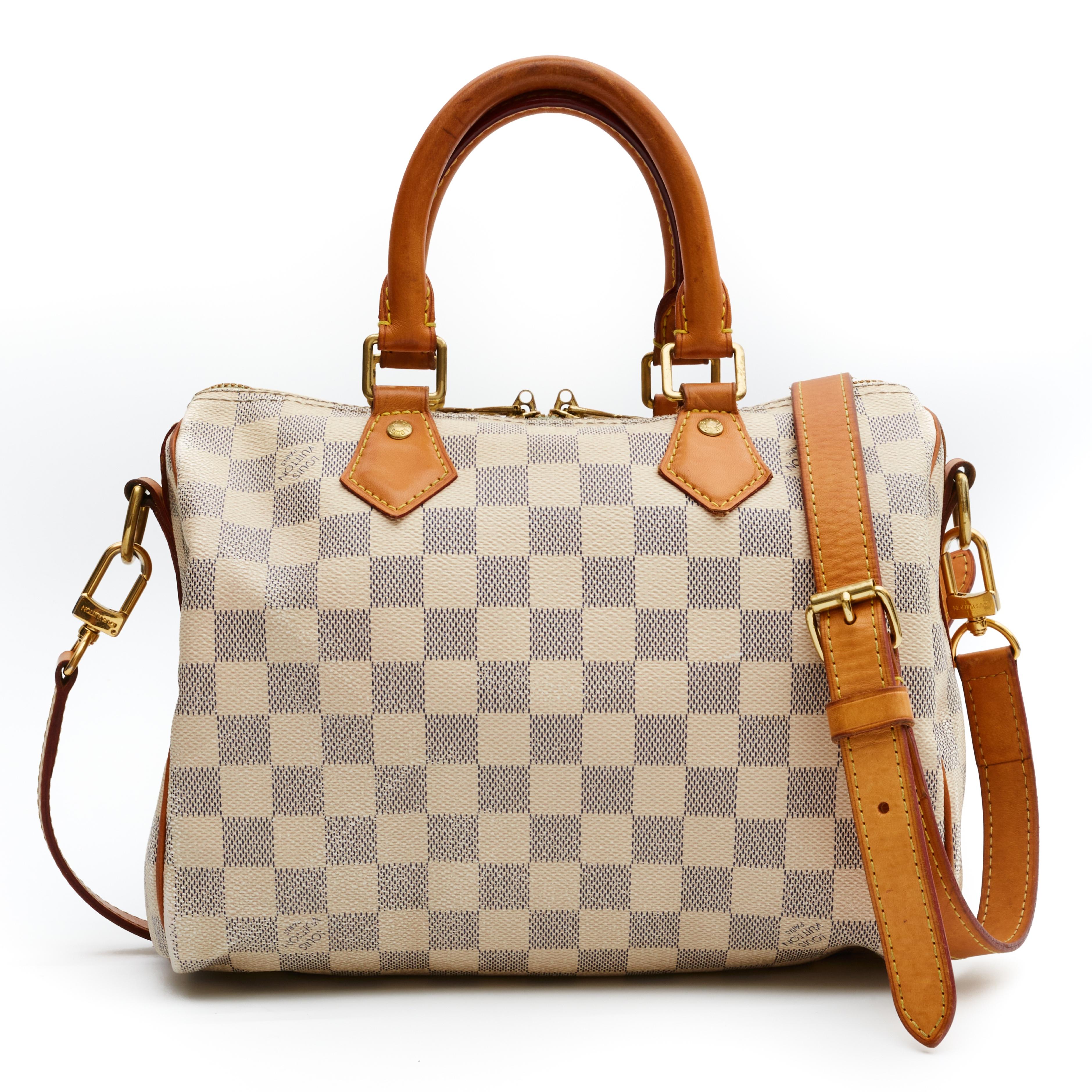 This style Speedy 25 Bandouliere (French for shoulder strap) is made with white canvas with Damier Azur print and features gold tone hardware, natural leather finishes, rolled leather handles, top zip closure and comes with an adjustable shoulder