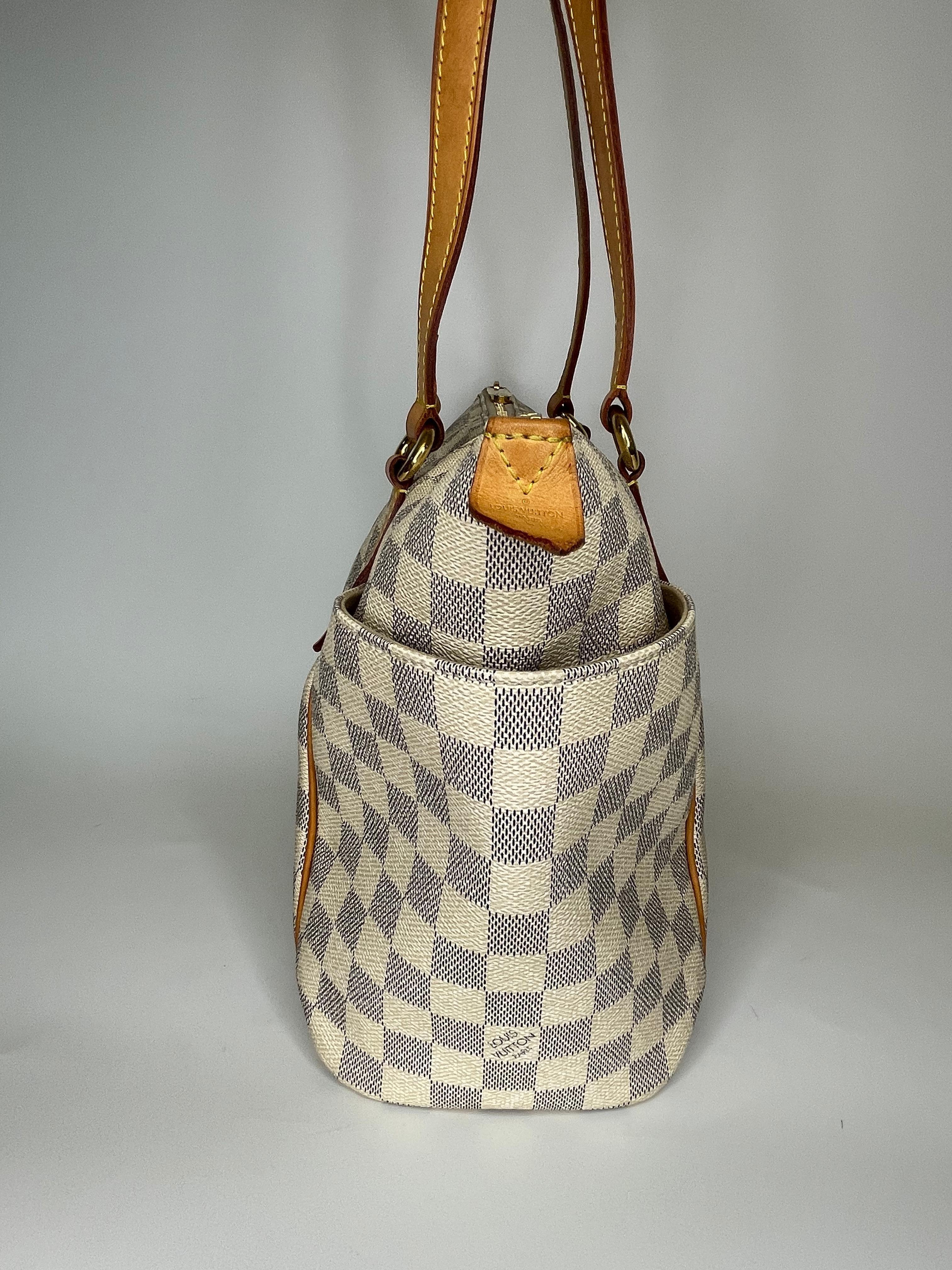 This style is called Totally and the bag is made with white coated canvas with Damier Azur pattern and features vachetta leather finishes, brass hardware, dual flat leather shoulder straps, exterior side pockets and fabric interior lining. (Damier