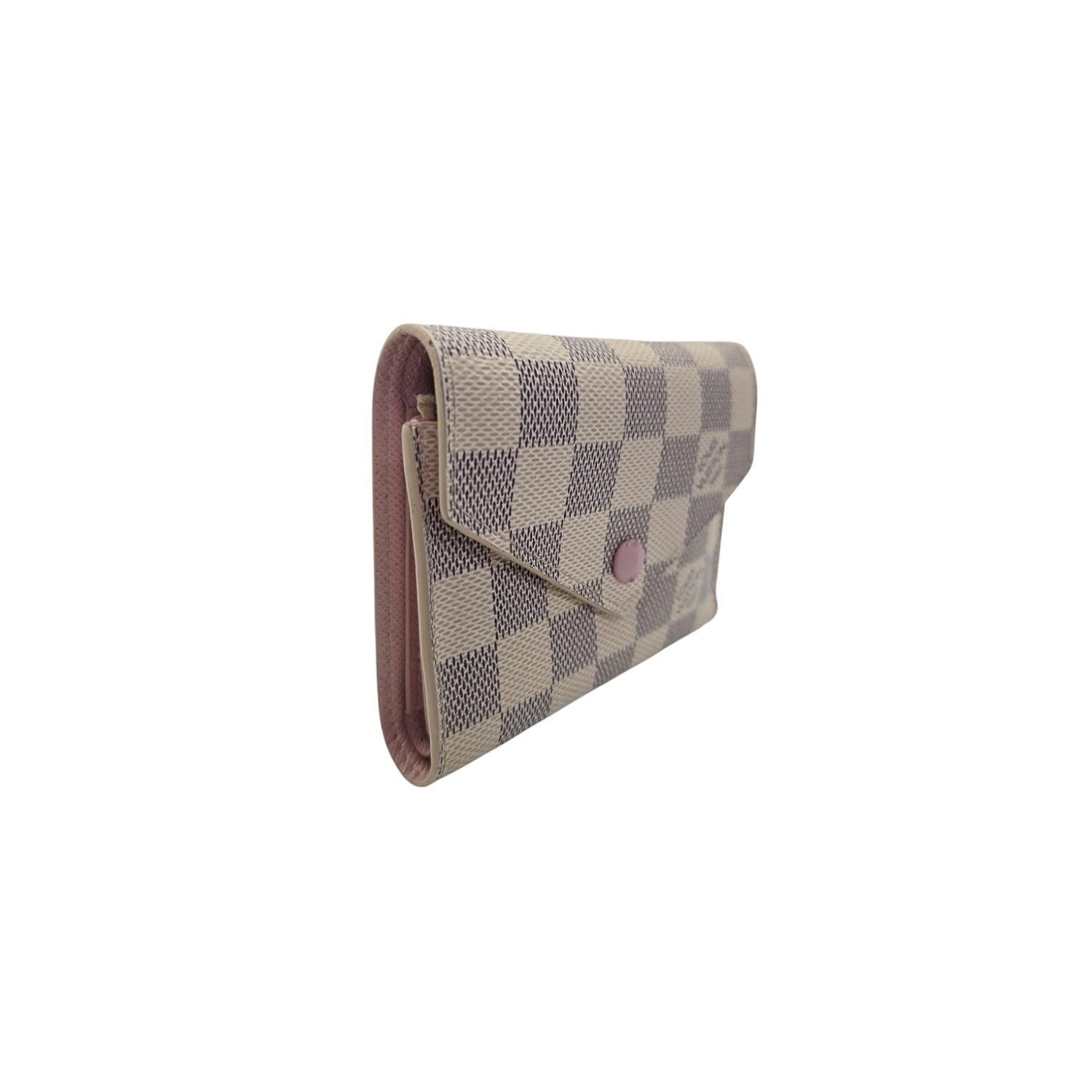 Louis Vuitton Damier Azur Victorine Wallet This compact wallet is crafted of Louis Vuitton Damier Azur Check Canvas in beige and blue. The wallet opens with a press stud to a Rose Ballerine pink interior with card slots, patch pockets, a billfold