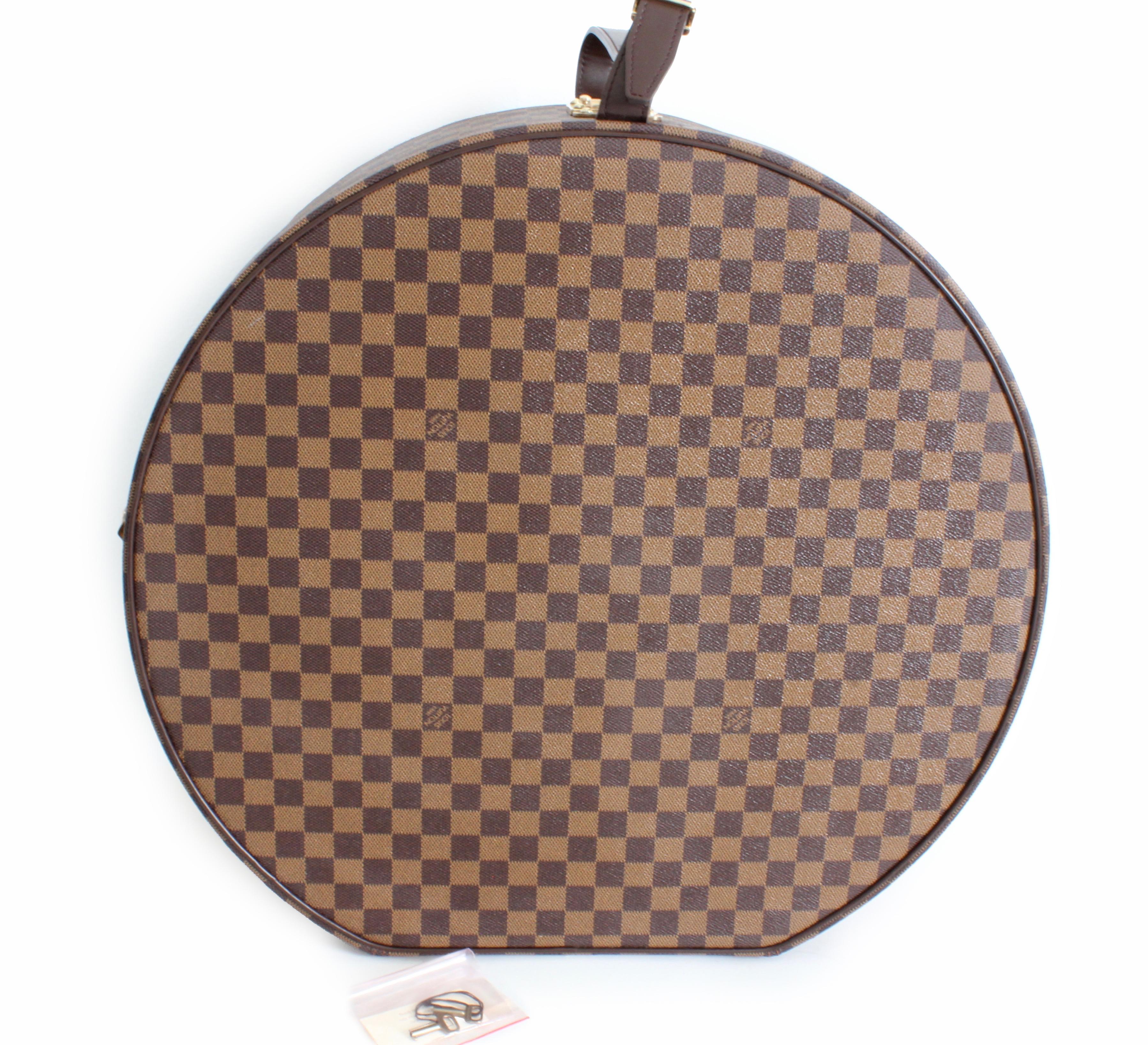 This large 50cm Damier Ebene Canvas hat box was made by Louis Vuitton in 2004.  It fastens with two side latches and one locking S-lock fastener.  Fully-lined in red fabric with an elasticized pocket.  Comes with it's original keys, too.  This piece