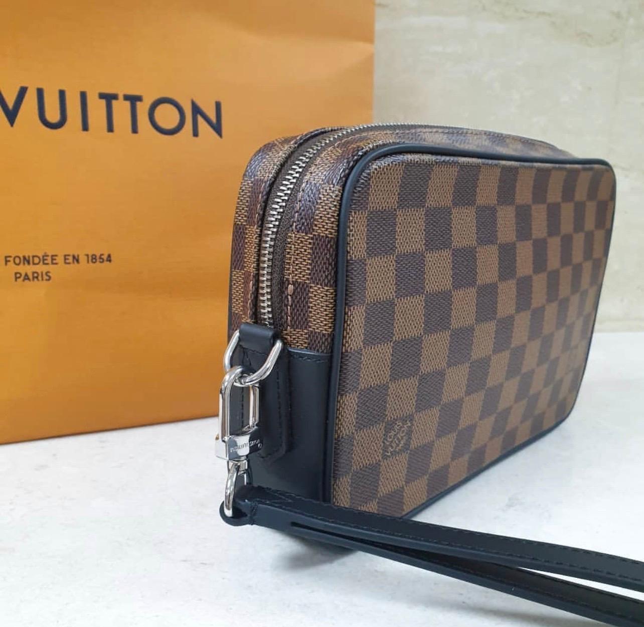 The Louis Vuitton Damier Canvas Kasai Clutch Bag is a classic silhouette that can be used as a clutch or cosmetic bag. 
The interior is large enough to hold your wallet, keys, and sunglasses! Its compact size and wristlet strap makes this perfect to
