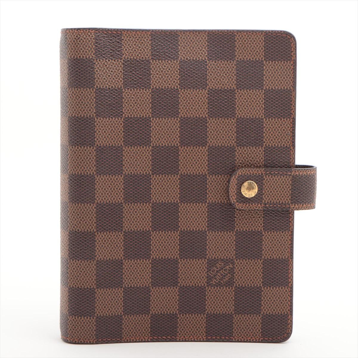 The Louis Vuitton Damier Ebene Agenda Notebook Cover is a sophisticated and versatile accessory for those who appreciate both style and organization. Crafted with the iconic Damier canvas, the notebook cover showcases the timeless elegance and