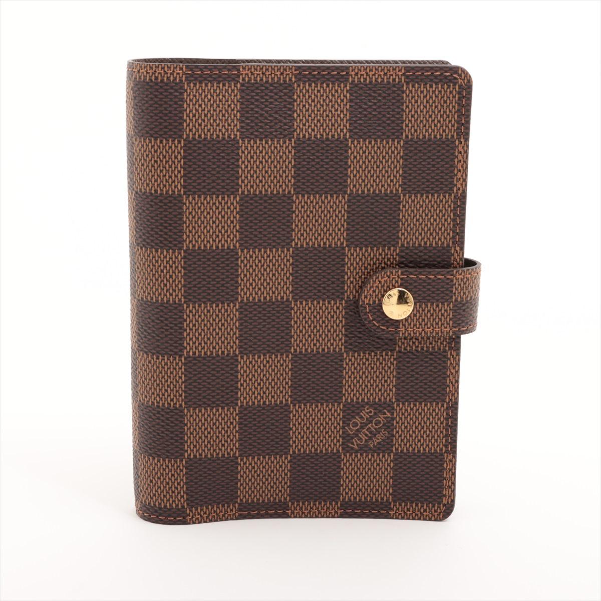 The Louis Vuitton Damier Ebene Agenda PM is a compact and elegant planner cover designed for organization with a touch of luxury. Crafted from iconic Damier Ebene coated canvas, the agenda features a durable and timeless checkerboard pattern with a