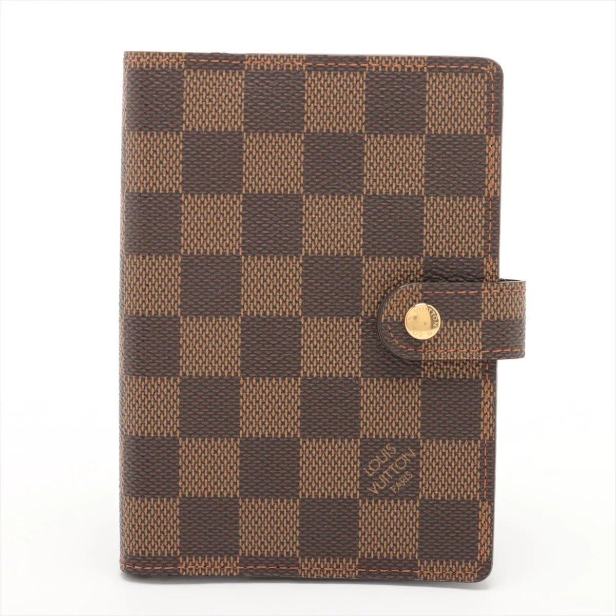 The Louis Vuitton Damier Ebene Agenda PM is a compact and elegant planner cover designed for organizations with a touch of luxury. Crafted from iconic Damier Ebene-coated canvas, the agenda features a durable and timeless checkerboard pattern with a