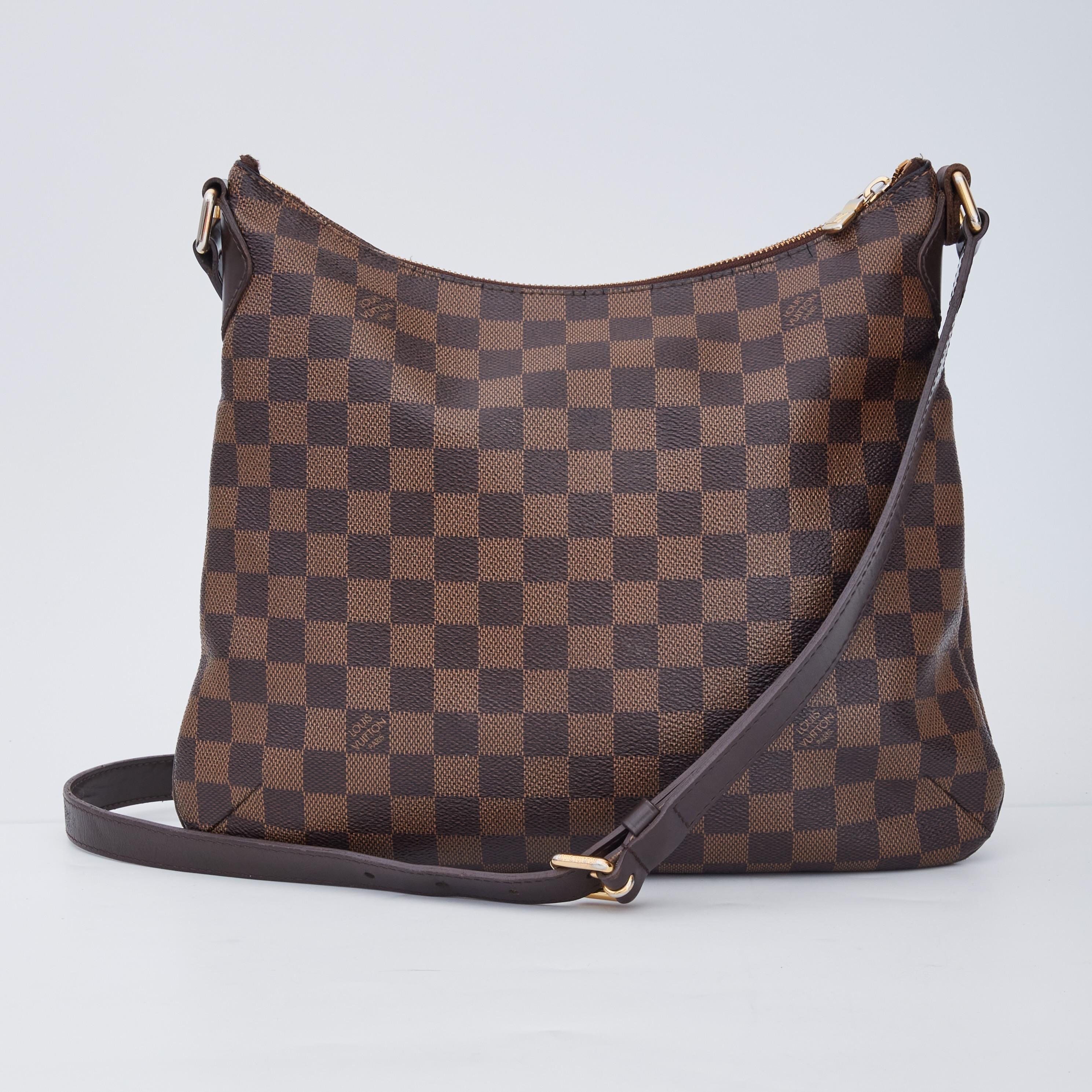 This shoulder bag is made of Louis Vuitton damier pleated coated canvas with a full facing patch pocket. The bag features a complimentary dark chocolate leather adjustable shoulder strap with a brass adjustment buckle and brass links. The top zipper