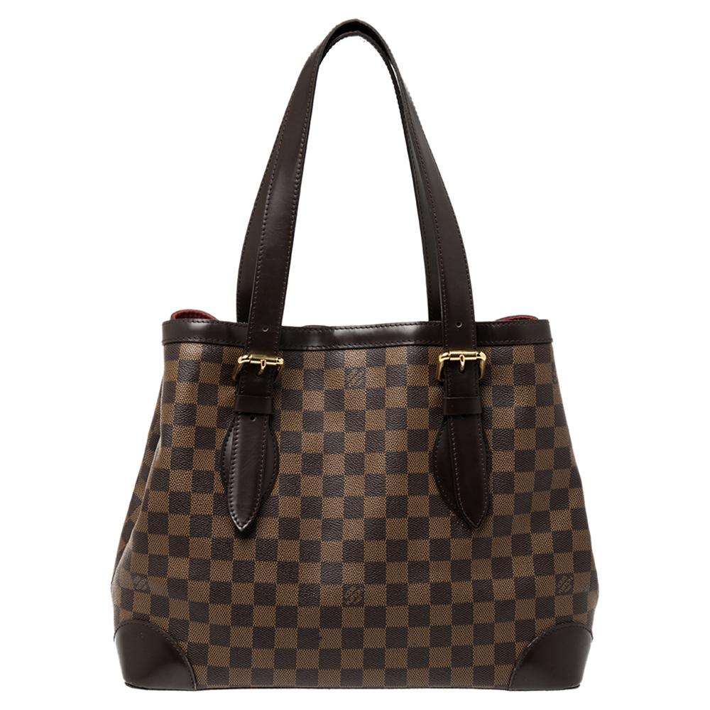 Handbags from Louis Vuitton enjoy widespread popularity owing to their high style and functionality. This Hampstead bag is no exception. Crafted from their signature Damier Ebene canvas and leather, the bag comes with two flat top handles and a hook