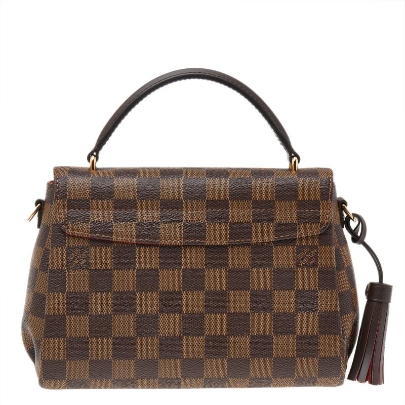Please your taste for luxury with this Croisette bag by Louis Vuitton. This structured beauty is crafted from the signature Damier Ebene canvas. It is detailed with a logo-engraved push-lock closure in gold-tone hardware along with a flat top handle