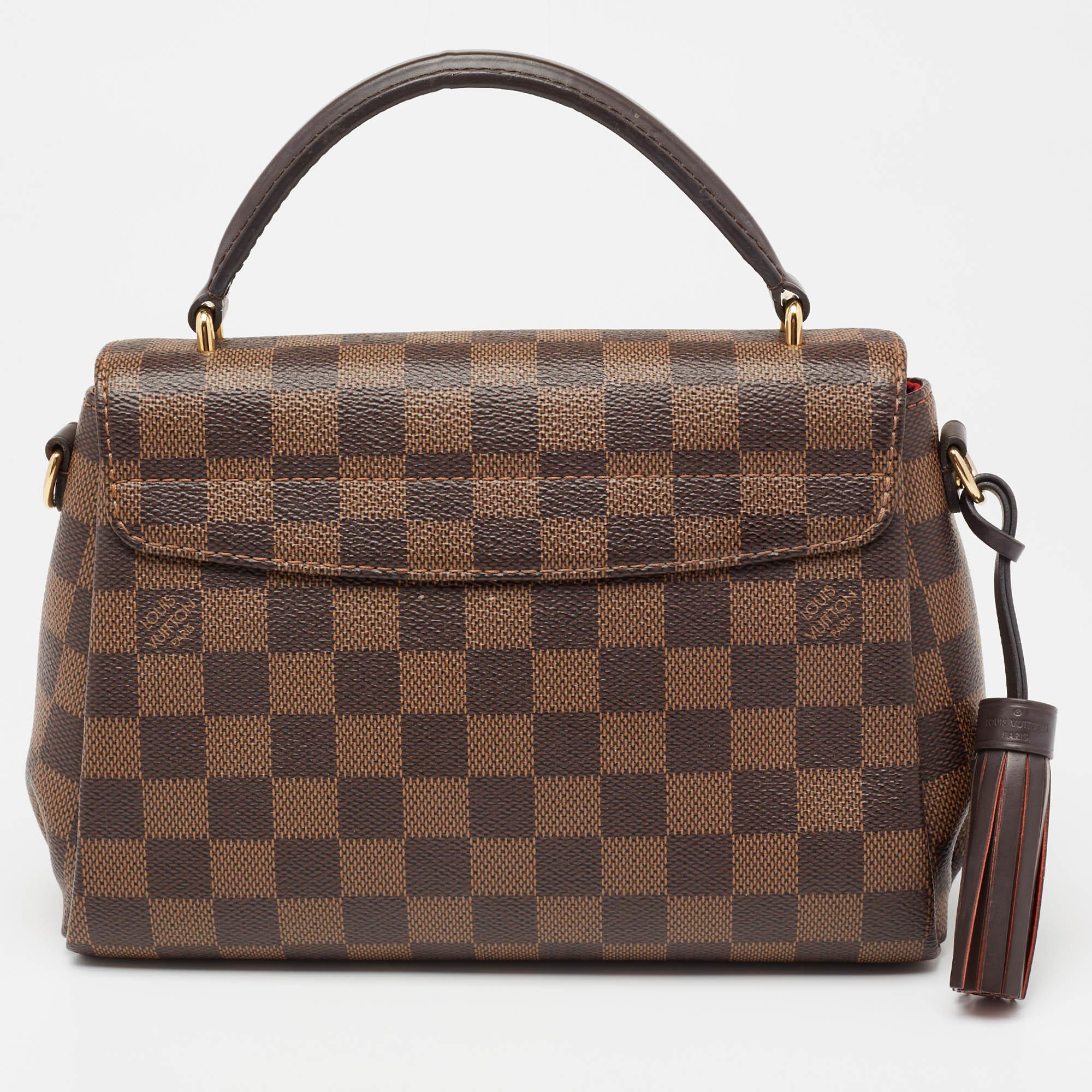 Treat yourself with this Croisette bag by Louis Vuitton. This structured style is crafted from the signature Damier Ebene canvas. It is detailed with a logo-engraved lock in gold-tone hardware, a top handle, and a slender shoulder strap for
