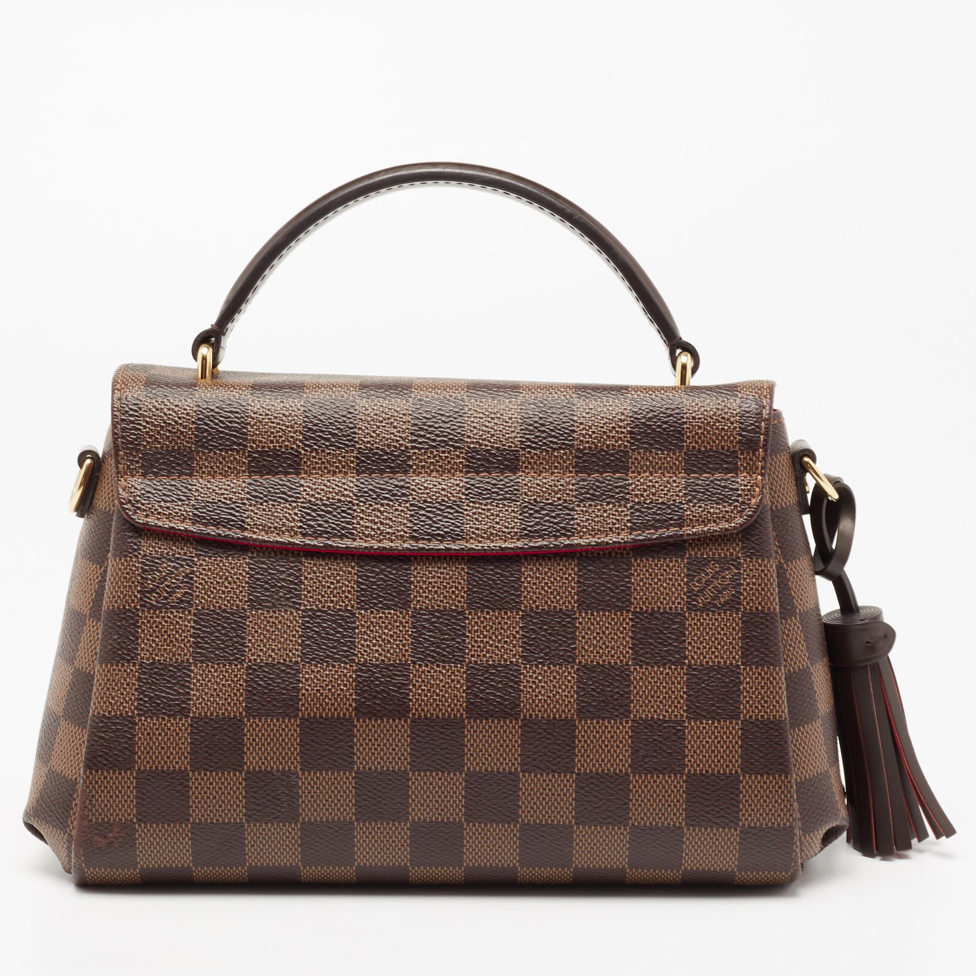 Treat yourself to this Croisette bag by Louis Vuitton. This structured style is crafted from signature Damier Ebene canvas. It is detailed with a gold-tone lock, a top handle, and a slender shoulder strap for crossbody wear. The well-sized interior