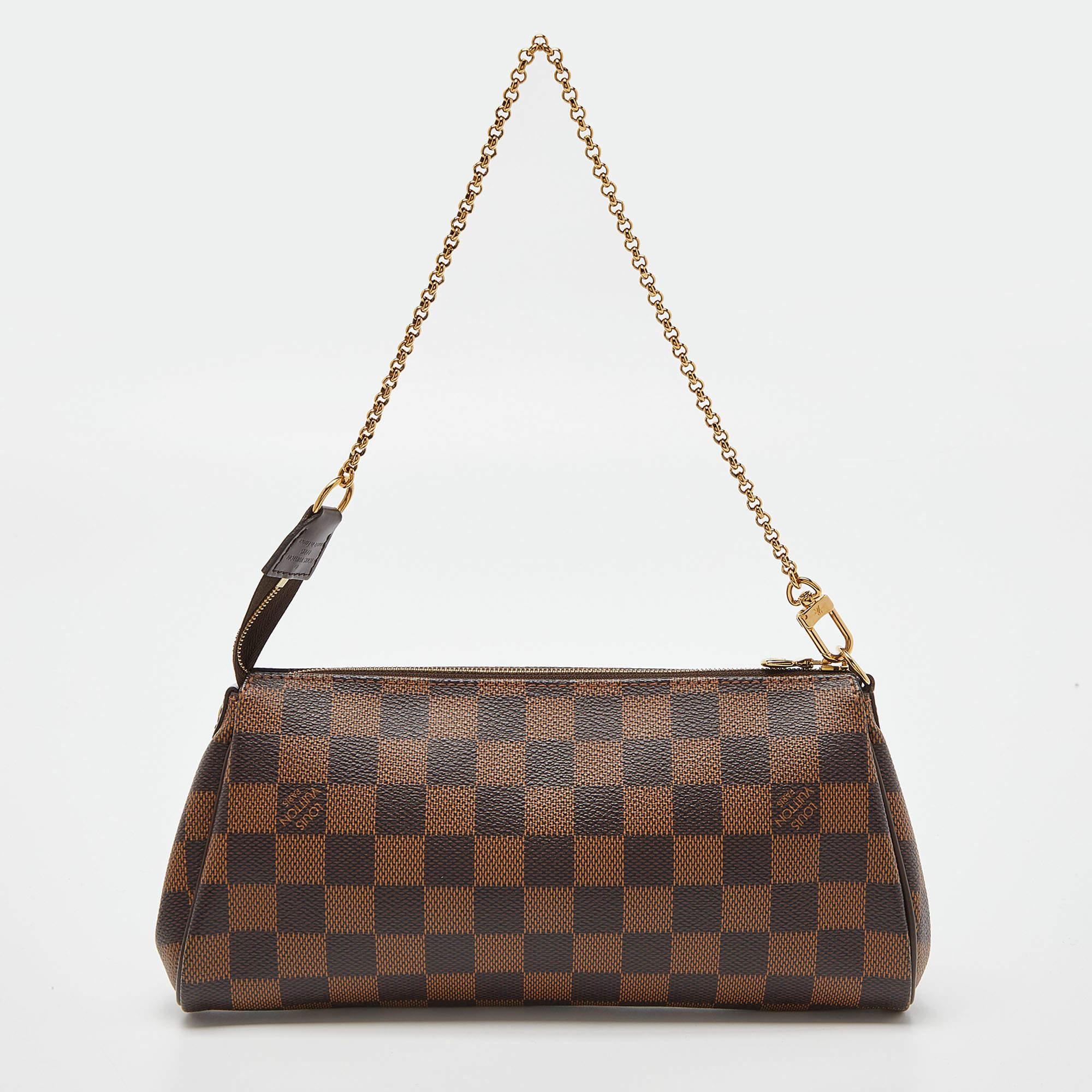 The Eva Pochette bag by Louis Vuitton showcases contemporary charm with its sophisticated shape. Made in France from Damier Ebene canvas, it features a detachable gold-tone chain handle and a top zipper. The metal plate engraved with the label's