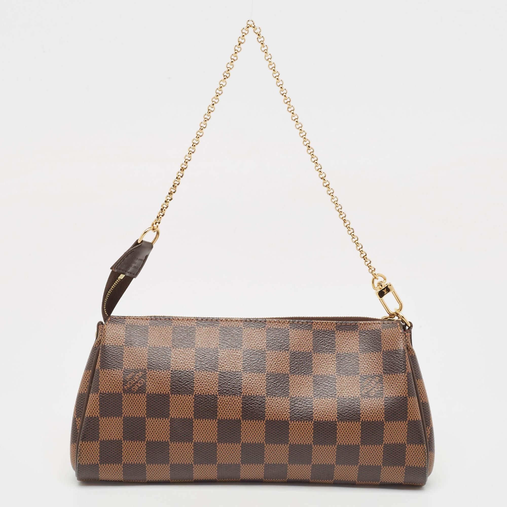 Crafted from Damier Ebene canvas, this Eva Pochette bag is a creation by Louis Vuitton. The bag features a well-sized canvas interior that is secured by a gold-tone zipper. The accessory comes with a chain handle, detachable leather strap, and brand