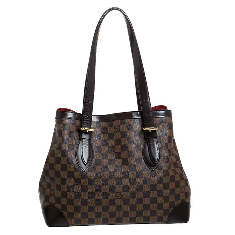 Handbags from Louis Vuitton enjoy widespread popularity owing to their high style and functionality. This Hampstead bag is no exception. Crafted from their signature Damier Ebene canvas, the bag comes with two flat top handles and a hook clasp that