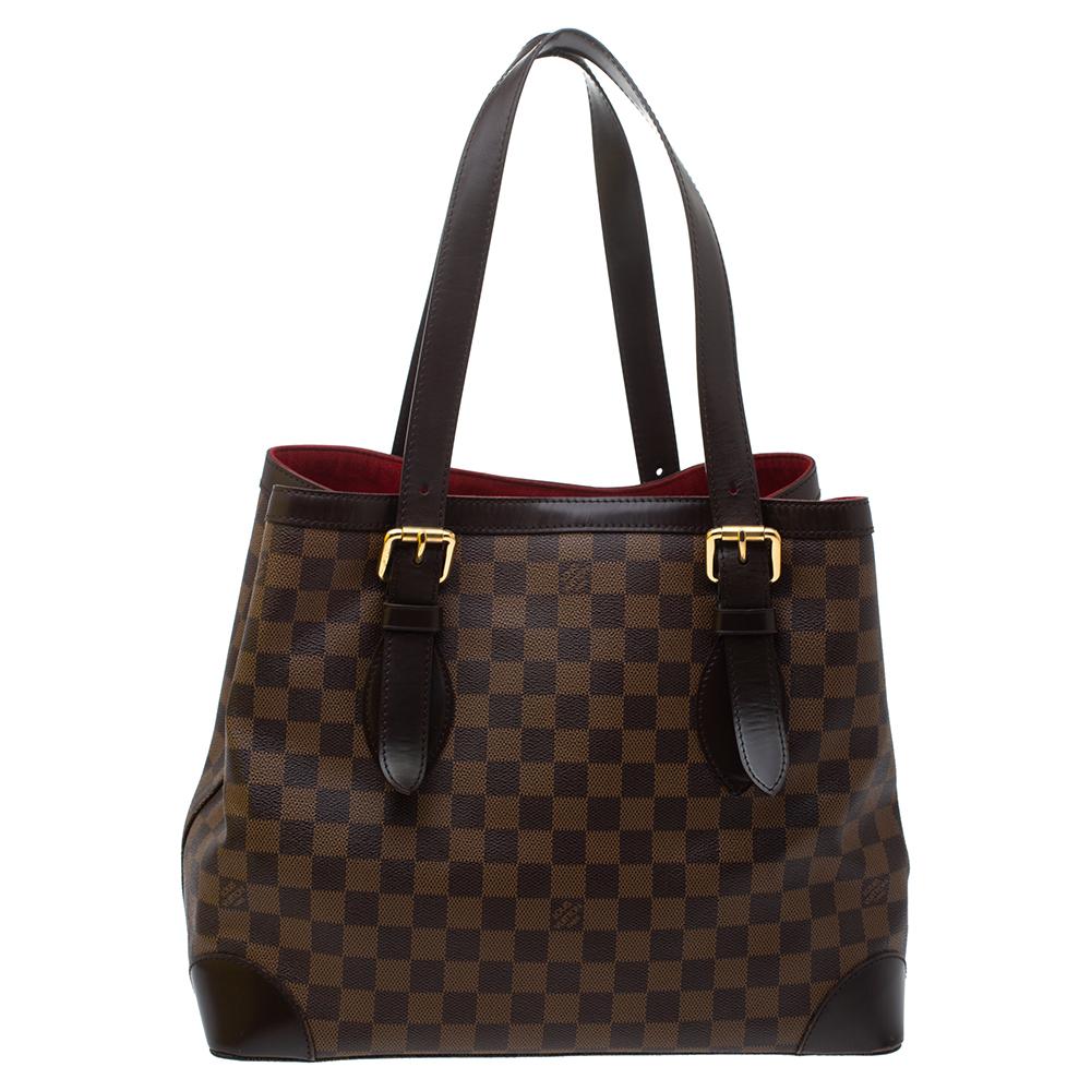Handbags from Louis Vuitton enjoy widespread popularity owing to their high style and functionality. This Hampstead bag, is no exception. Crafted from their signature Damier Ebene coated canvas, the bag comes with two flat top handles and a hook