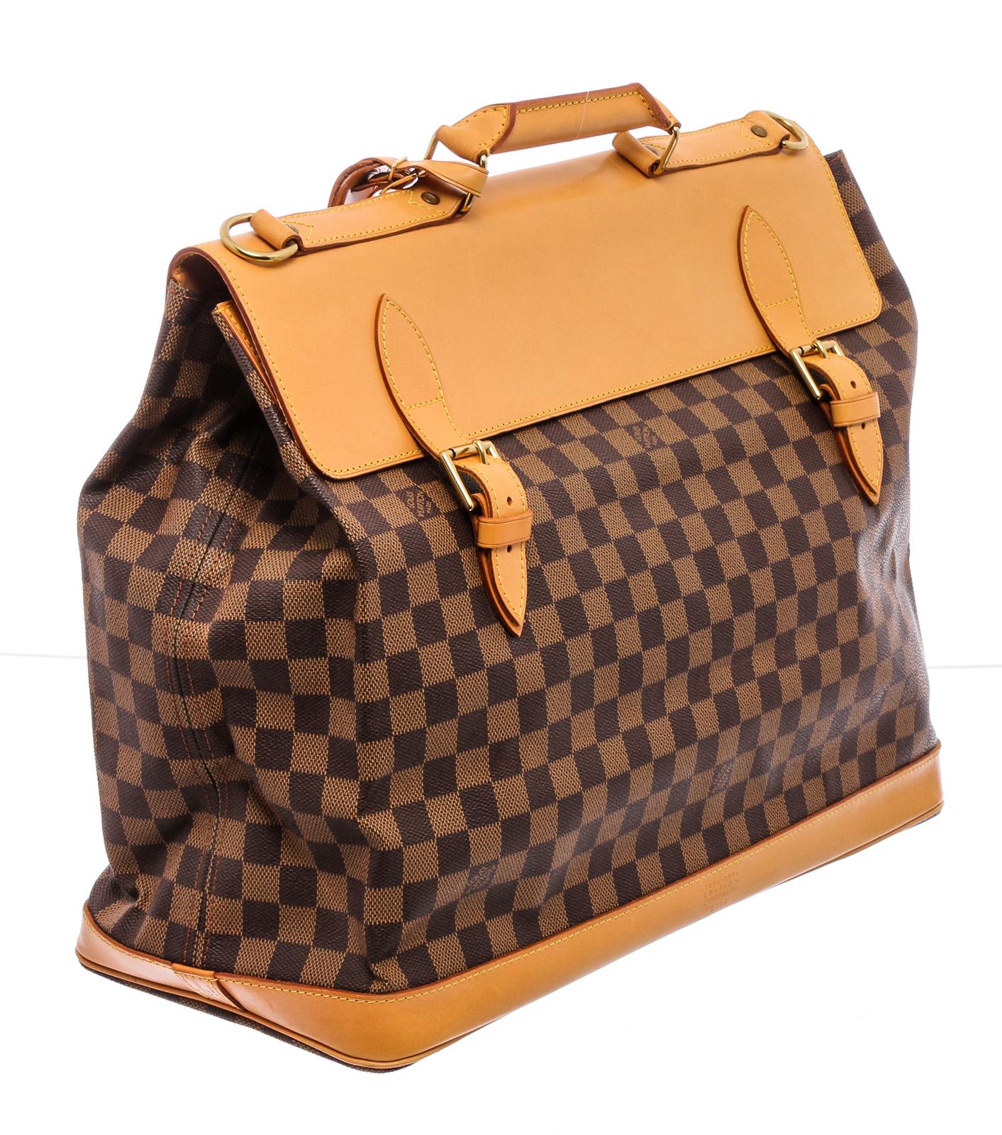 Limited 100 Year Anniversary Edition Louis Vuitton Centenaire West End travel bag is crafted of Damier check toile canvas in brown. The bag features extensive vachetta cowhide leather embellishment including a sturdy top handle with brass links,