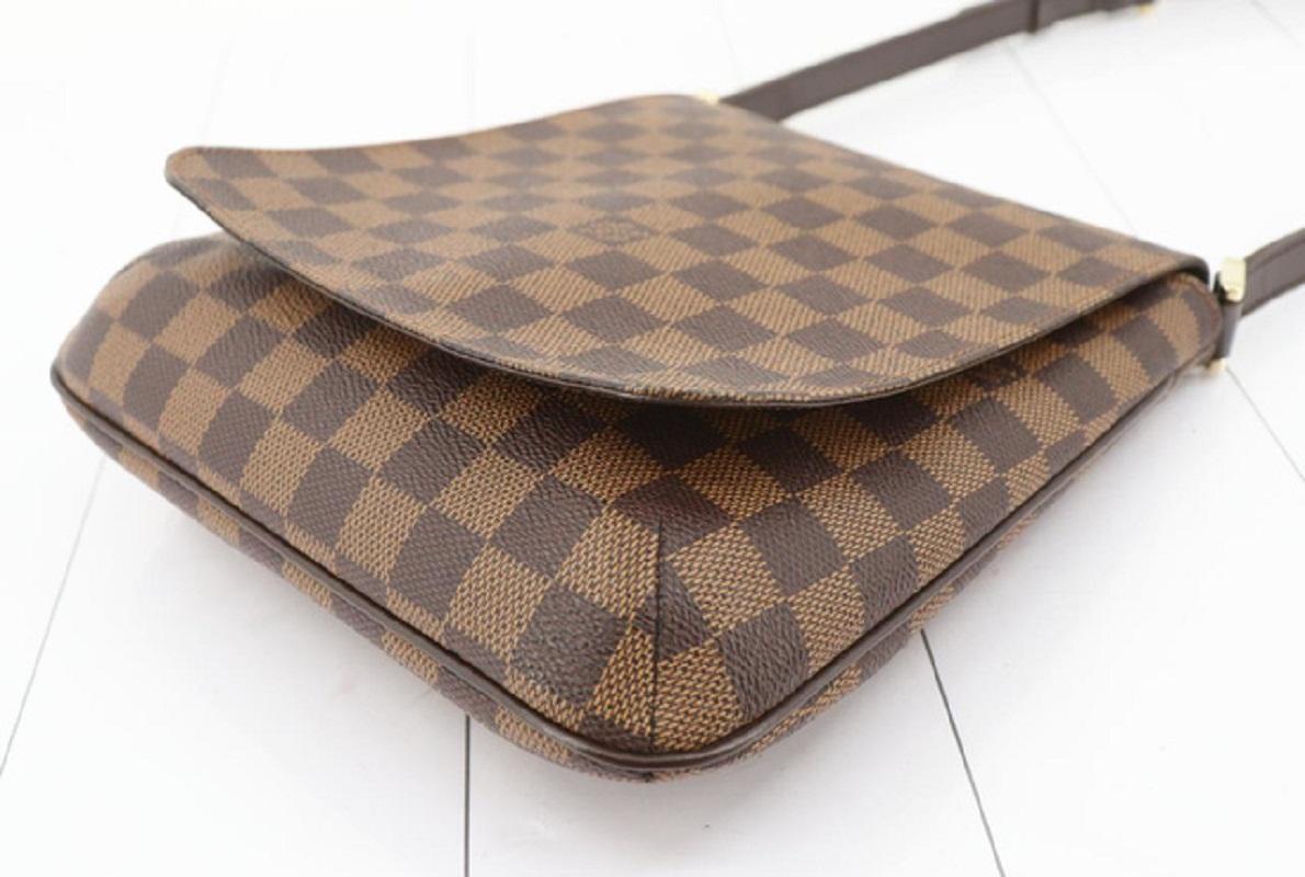 Brown and tobacco Damier Ebene coated canvas Louis Vuitton Musette Salsa PM with gold-tone hardware, tan vachetta leather accents, single short flat shoulder strap, cinnamon Alcantara lining, single slit pocket at interior wall and snap closure at