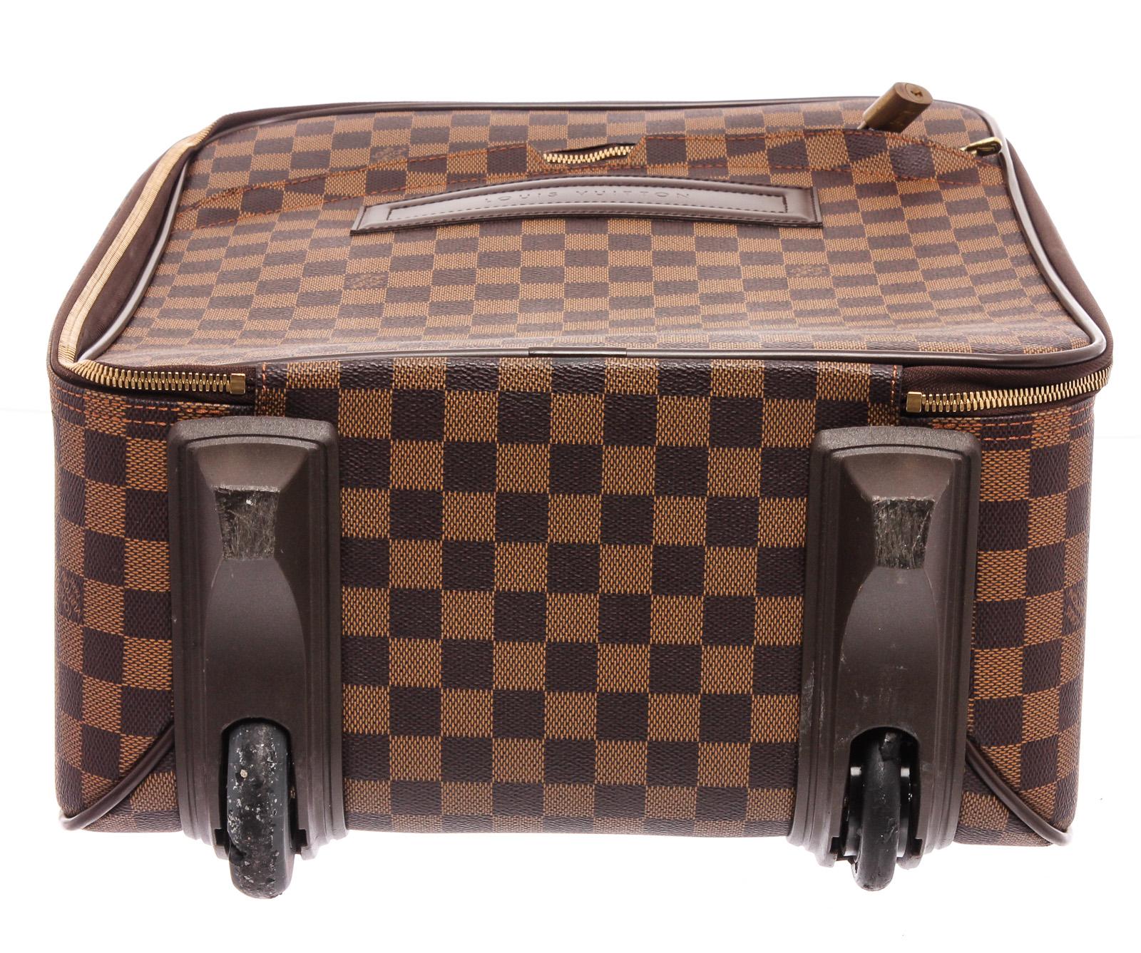 Brown and tan Damier Ebene coated canvas Louis Vuitton Pegase with brass hardware, tan vachetta leather trim, single pocket at exterior, dual flat handles at exterior, single telescopic handle, brown canvas lining, single zip pocket and two-way all