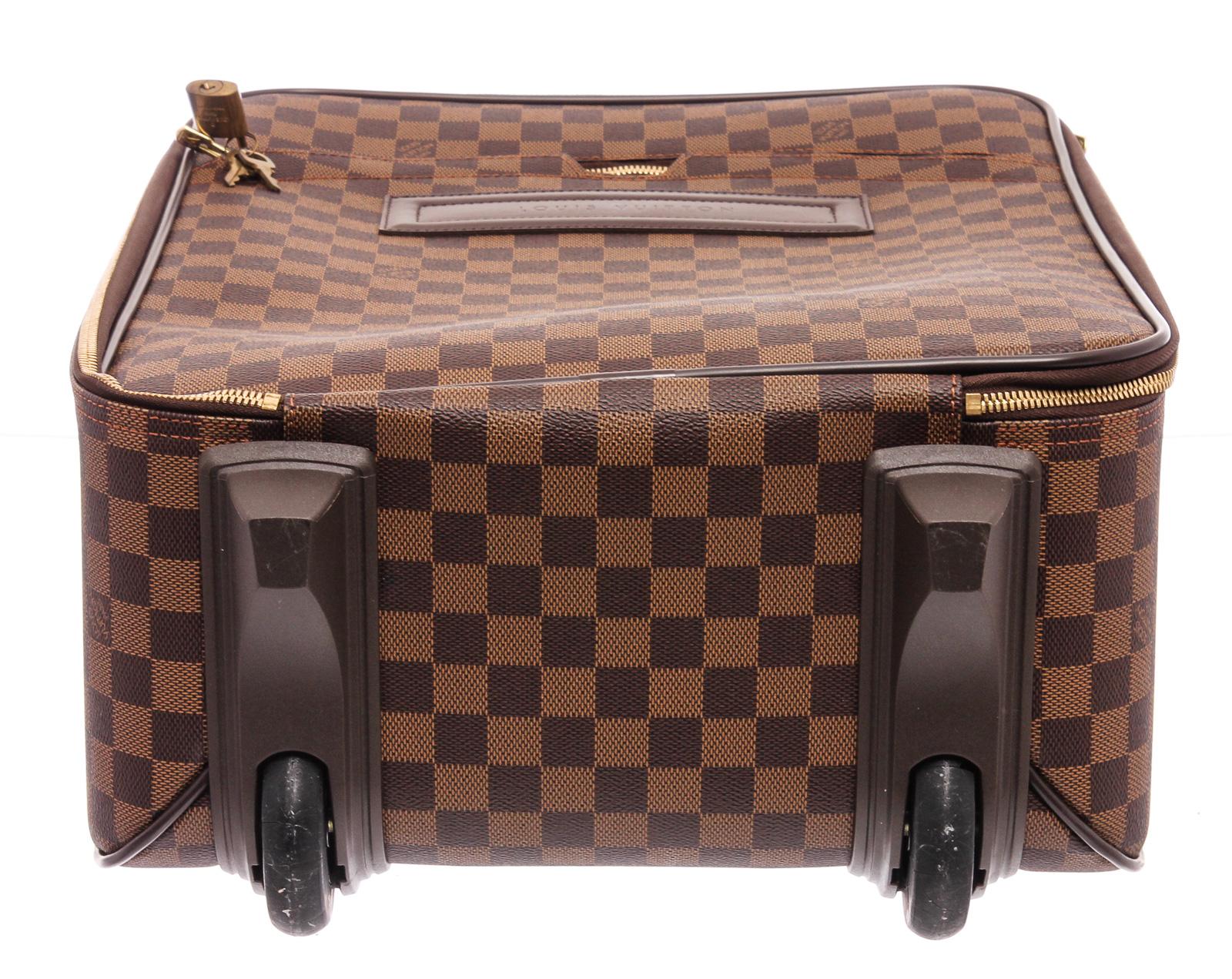 Brown and tan Damier Ebene coated canvas Louis Vuitton Pegase with brass hardware, tan vachetta leather trim, single zip pocket at exterior, dual flat handles at exterior, single telescopic handle, brown canvas lining, single zip pocket and two-way