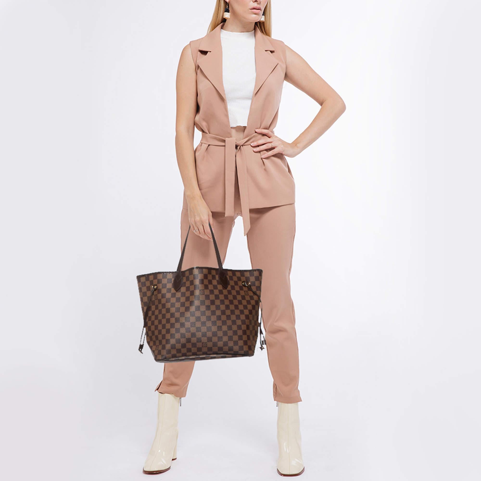 Recognized as one of the most exemplary creations of the house this stunning Neverfull bag from Louis Vuitton is designed to offer luxury with never ending elegance. It exhibits Damier Ebene canvas on the exterior with distinct gold toned hardware