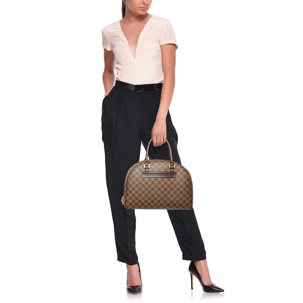 This Louis Vuitton Nolita bag brings you the best of craftsmanship and classic appeal. Crafted using Damier Ebene canvas, this timeless gem, featuring dual handles, a spacious interior, and gold-tone hardware, will be an excellent addition to your
