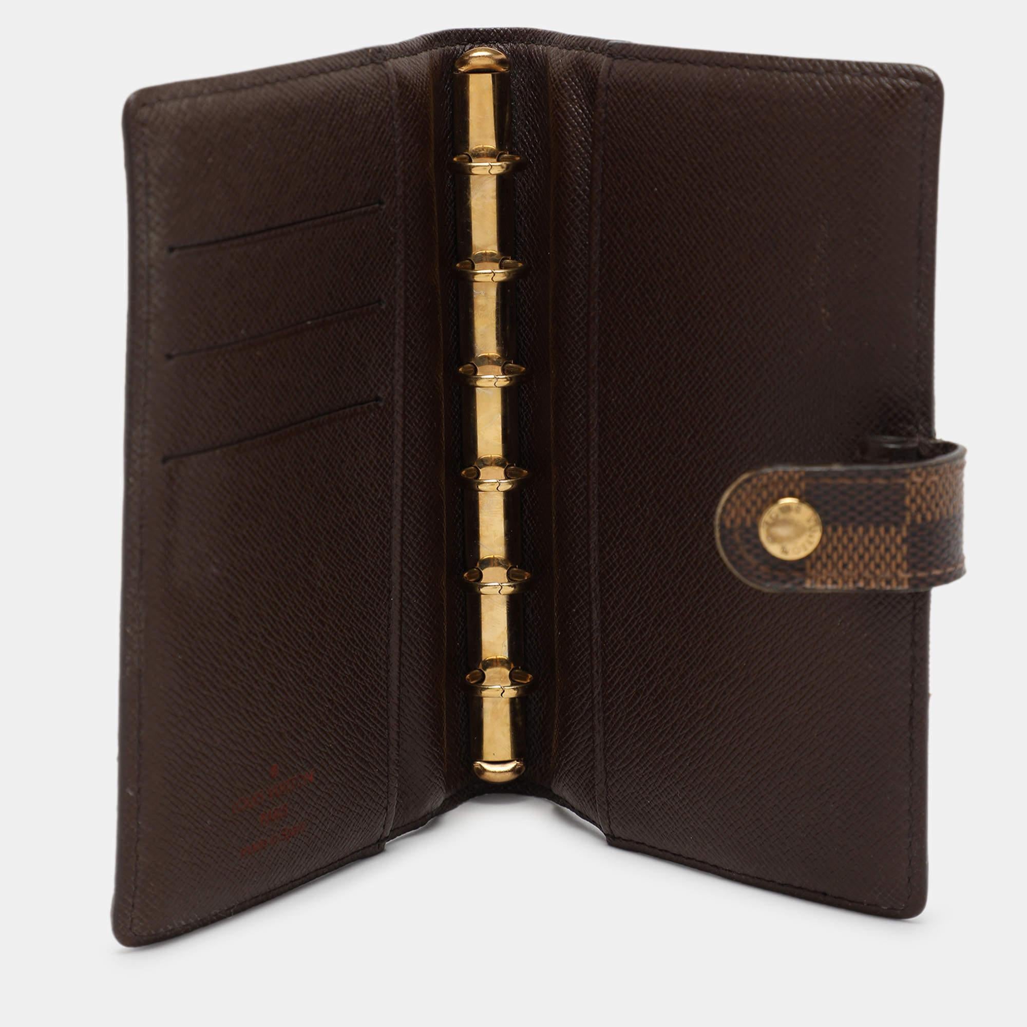The Louis Vuitton Agenda Cover is a chic and functional accessory crafted from the brand's iconic checked canvas. With sleek leather trim and a gold tone ring binder it offers organized sophistication for daily planning. Its compact size makes it