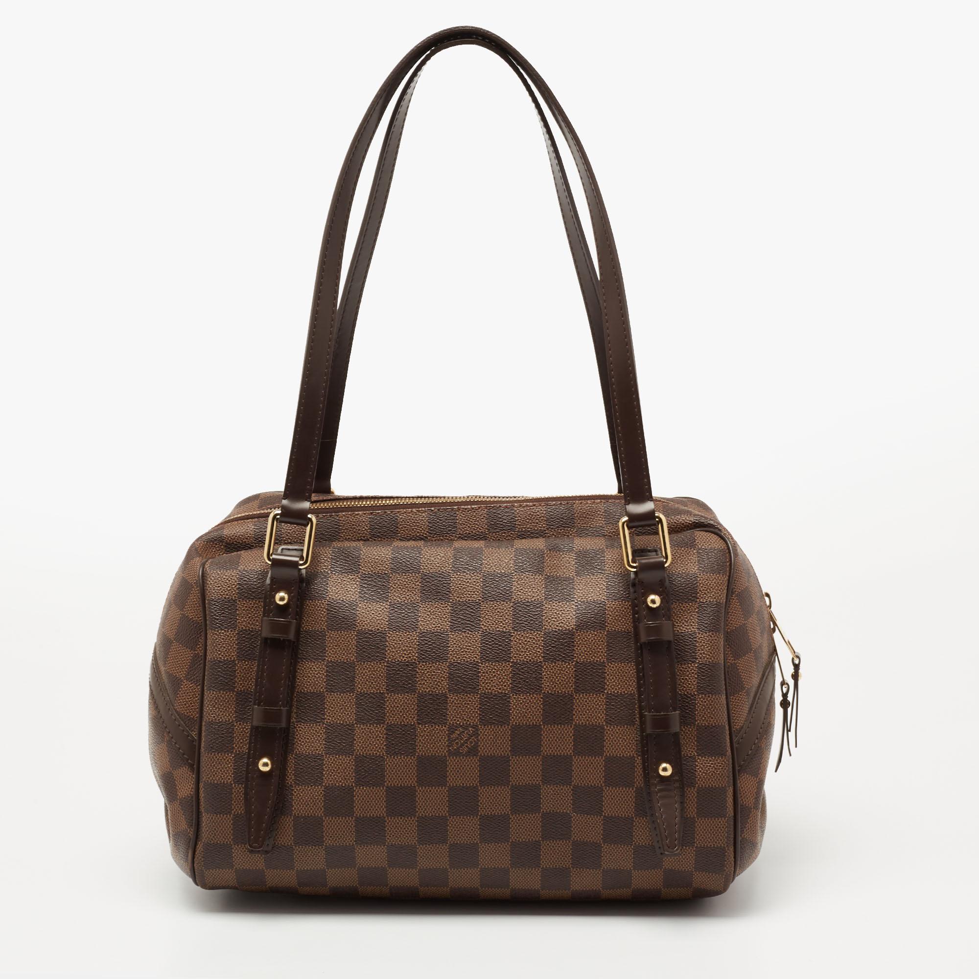 This Louis Vuitton Rivington GM bag has the perfect fusion of fashion and practicality. Constructed from the signature Damier Ebene canvas, it embodies a minimalistic design with an elegant touch. It is defined by dual handles at the top, a brand