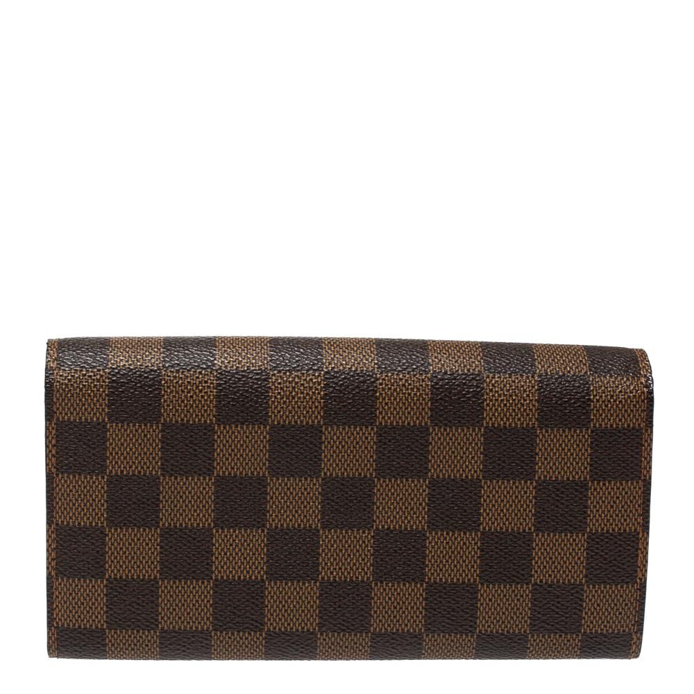 One of the most famous wallets by Louis Vuitton is the Sarah. This one here comes made from Damier Ebene canvas and the button on the flap opens to an interior with multiple card slots and a zip pocket. Perfect in size, this wallet can easily fit