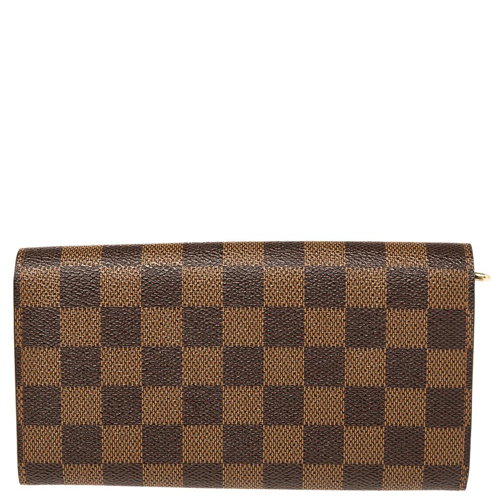 One of the most famous wallets by Louis Vuitton is the Sarah. This one here comes made from Damier Ebene canvas and the button on the flap opens to an interior with multiple card slots and a zip pocket. Perfect in size, this wallet can easily fit